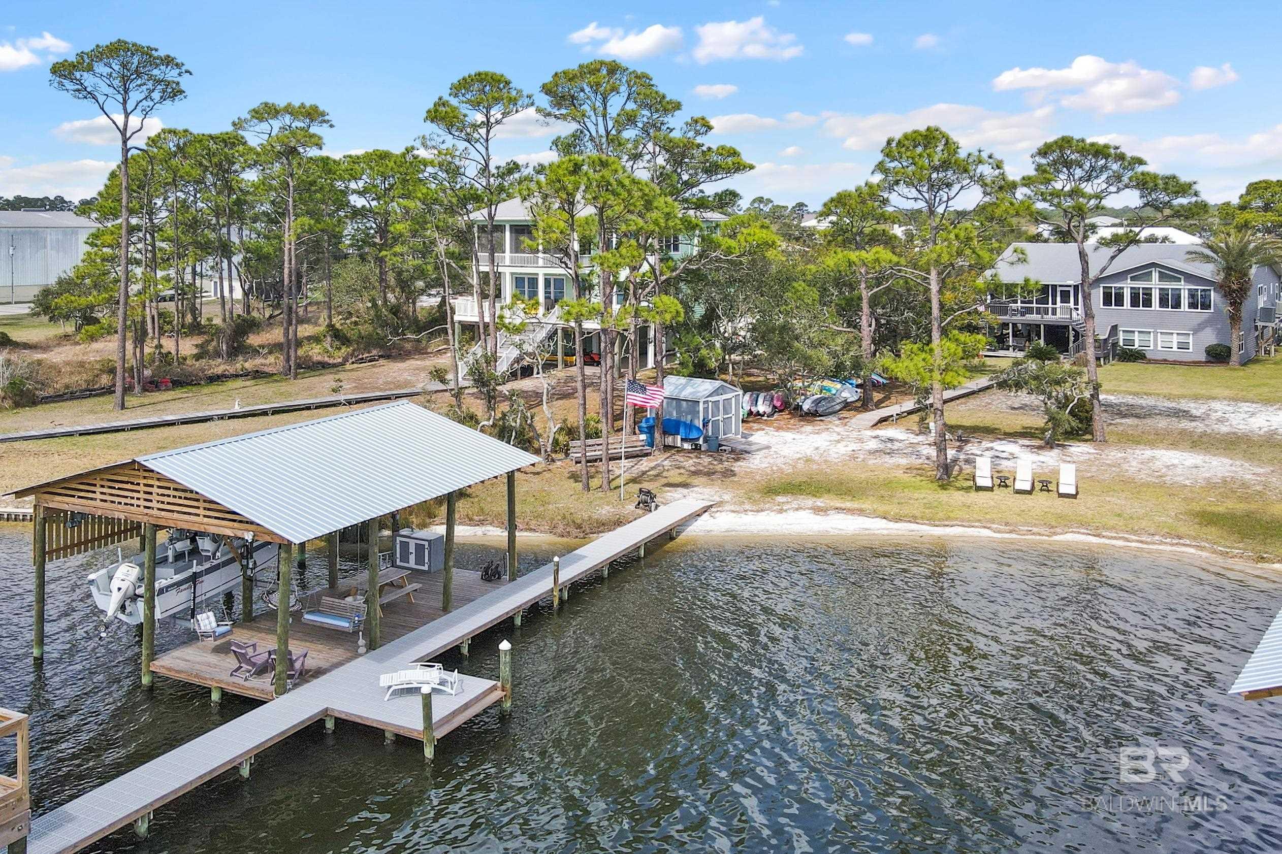 COTTON BAYOU WATERFRONT says it all...  This Unique and Rare find offers the absolute perfect waterfront home, whether for retirement, vacation, or year around living. This 4 bedroom and 4 and 1/2 bath home had a major renovation completed in 2004 and a whole house update completed in 2021. (Check out the property photos). The panoramic views of Cotton Bayou are seen from most rooms and levels of this beautiful home. The main level offers a huge Great room with vaulted ceilings, picturesque windows, and big views as does the main bedroom. The main bedroom is very spacious and has two walk-in closets and two private baths. Other features included in this open floor plan is a fully equipped kitchen, woodburning fireplace, additional living room space along with two guest bedrooms and the 3rd bath. The first-floor level offers a large Den/Recreational room perfect for that pool table you been wanting or just a great gathering spot from a day on the water. This level also has a guest suite with full bath and a large office space. Other property features include: board walk down to your private boat dock, two boat houses with power lifts, covered decks, sun decks, and your own little sandy beach. This property also has plenty of parking along with a double garage as well as a second detached double garage for the toys. One of the very best features of this beautiful property is the location at which you are to Perdido Pass into the Gulf of Mexico as well as all the other water ways abundant to the Orange Beach communities. I could go on and on but the best thing to do at this point is to contact your Real Estate Agent and to make arrangements for your personal private showing.