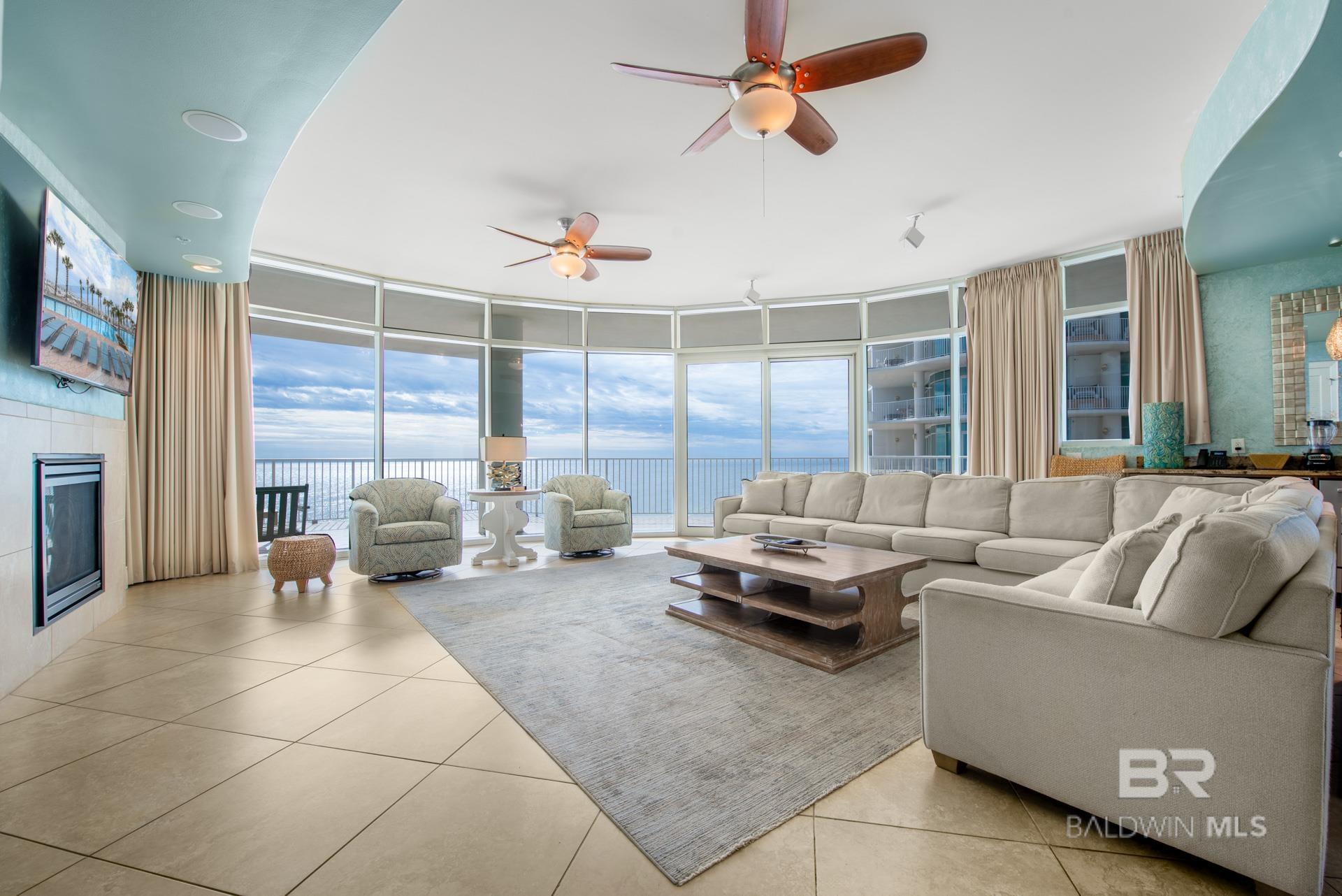 Tiled living room featuring a water view, ceiling fan, and floor to ceiling windows