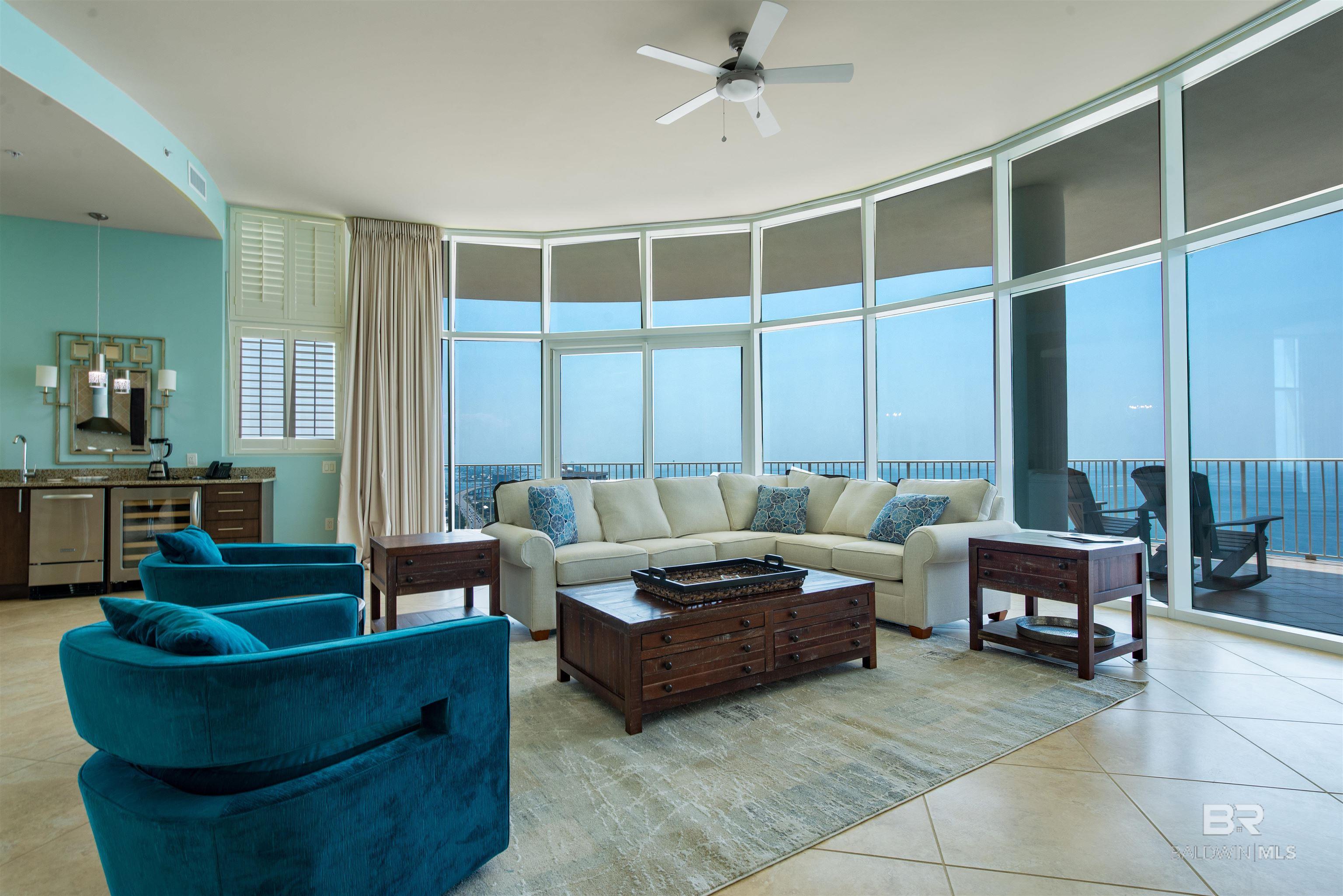 Living room featuring expansive windows, light tile patterned floors, wine cooler, and ceiling fan