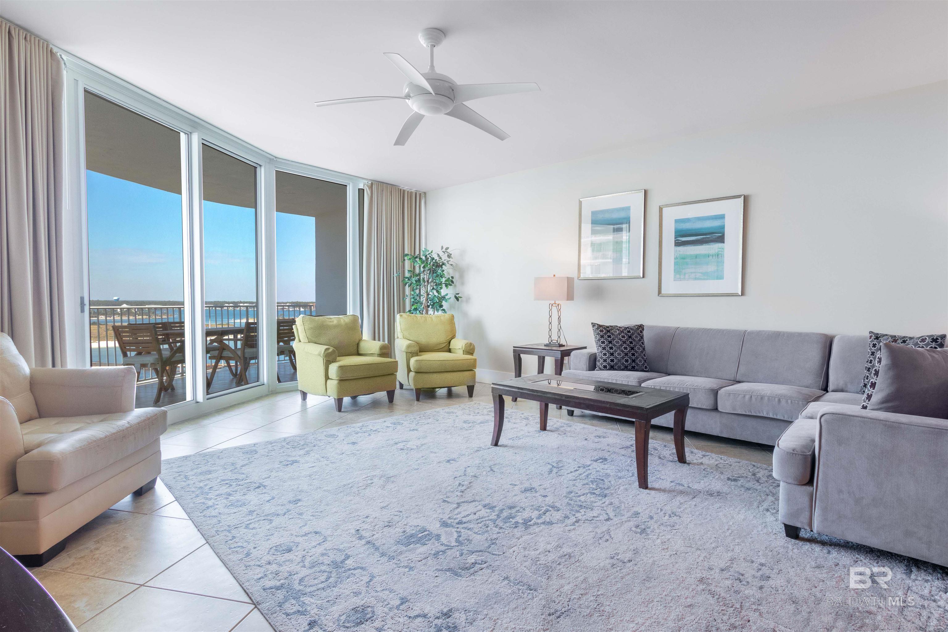 Living area with light tile patterned floors, expansive windows, and a ceiling fan