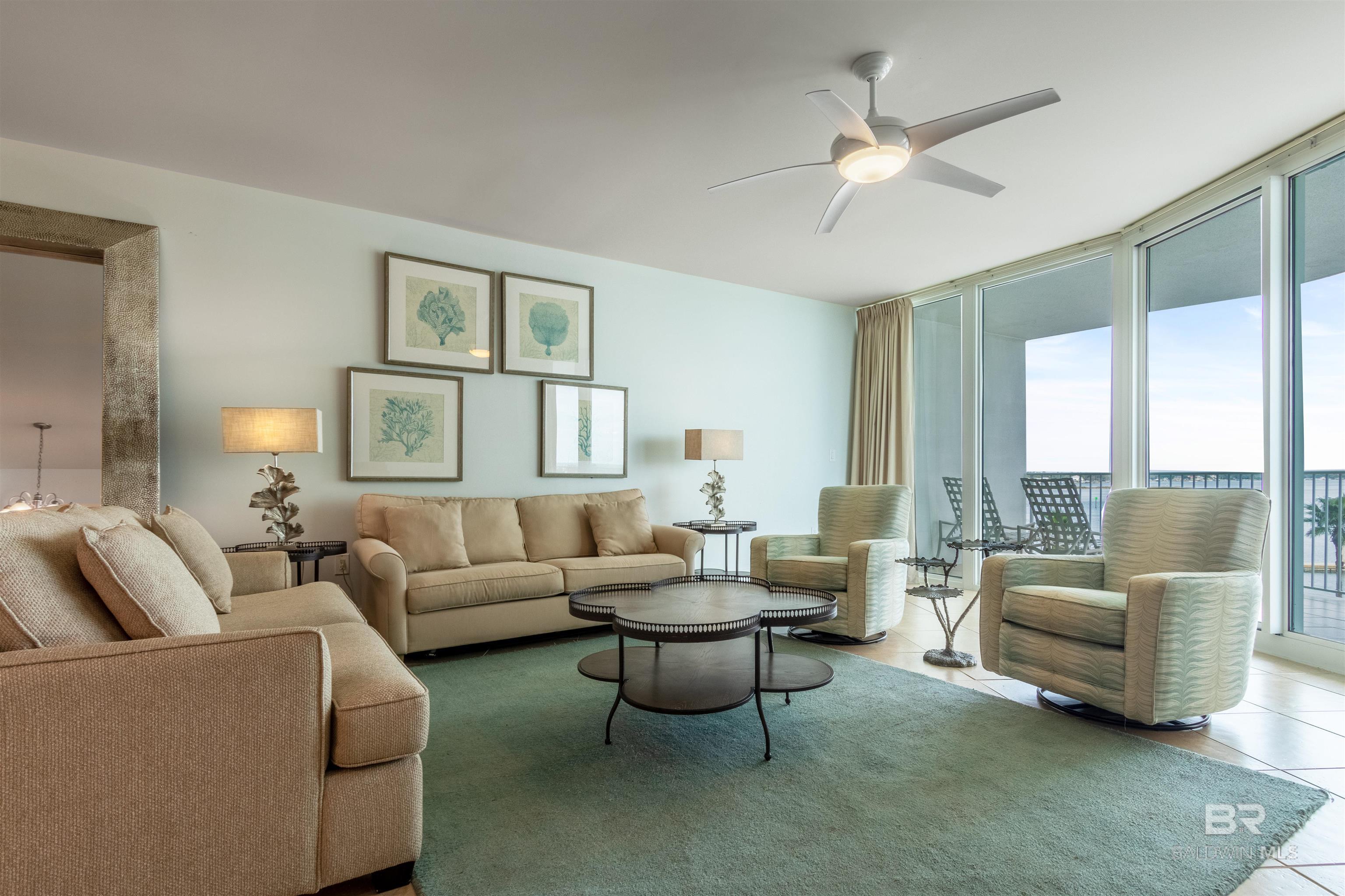 Living area with a ceiling fan, expansive windows, and light tile patterned floors