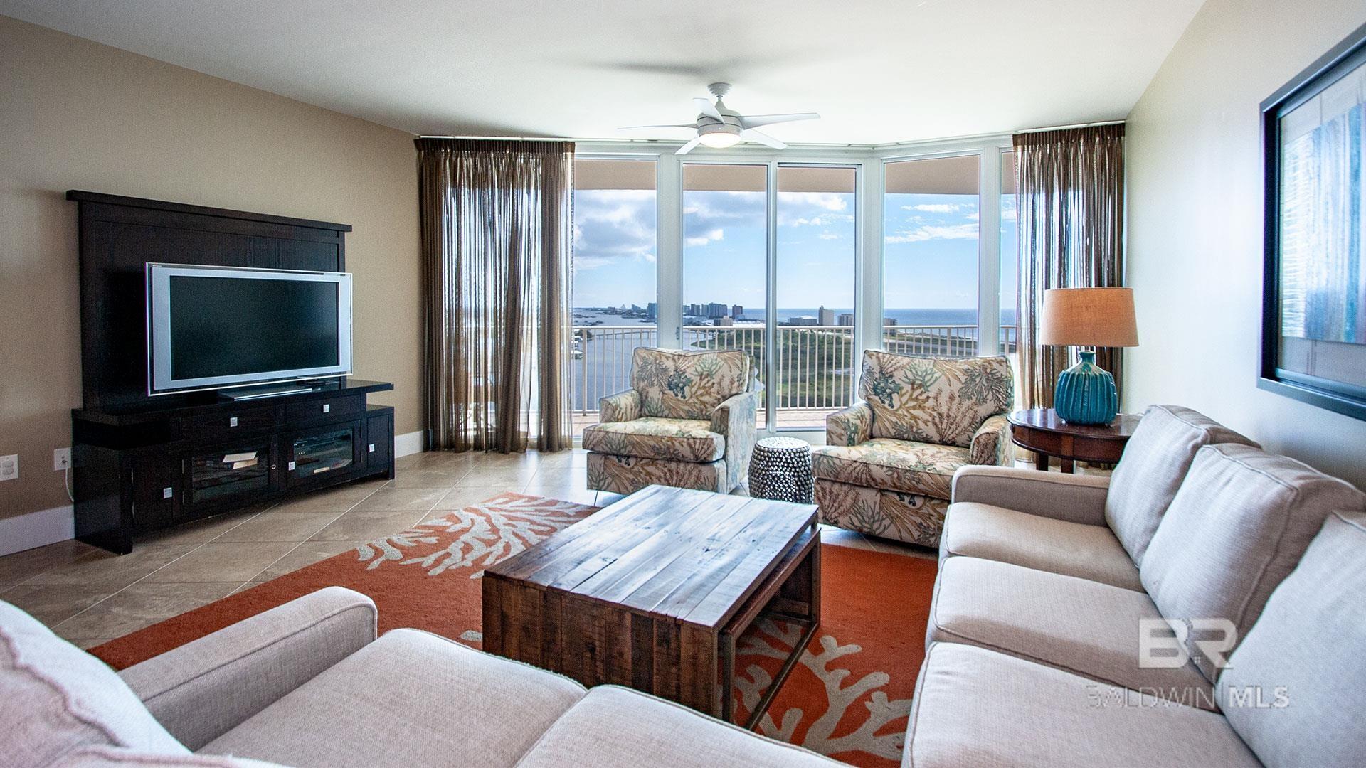 Living area featuring ceiling fan, healthy amount of natural light, tile patterned floors, expansive windows, and baseboards