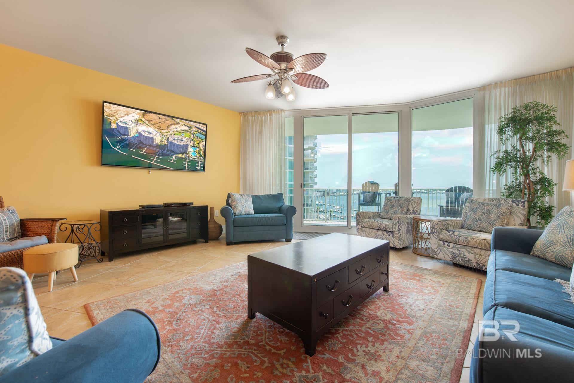 Tiled living area featuring a ceiling fan and expansive windows