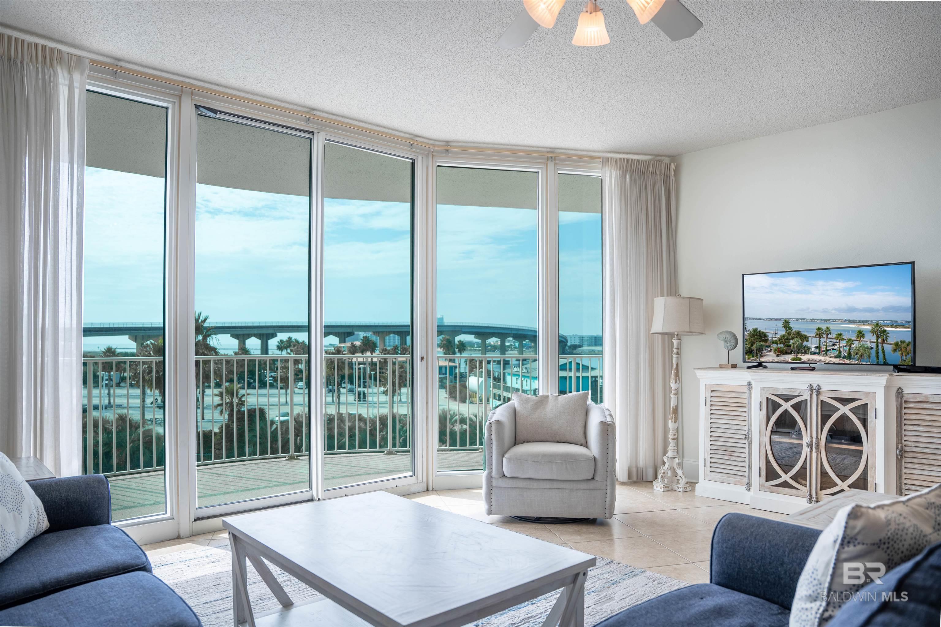 Living room featuring expansive windows, a textured ceiling, healthy amount of natural light, a water view, and ceiling fan