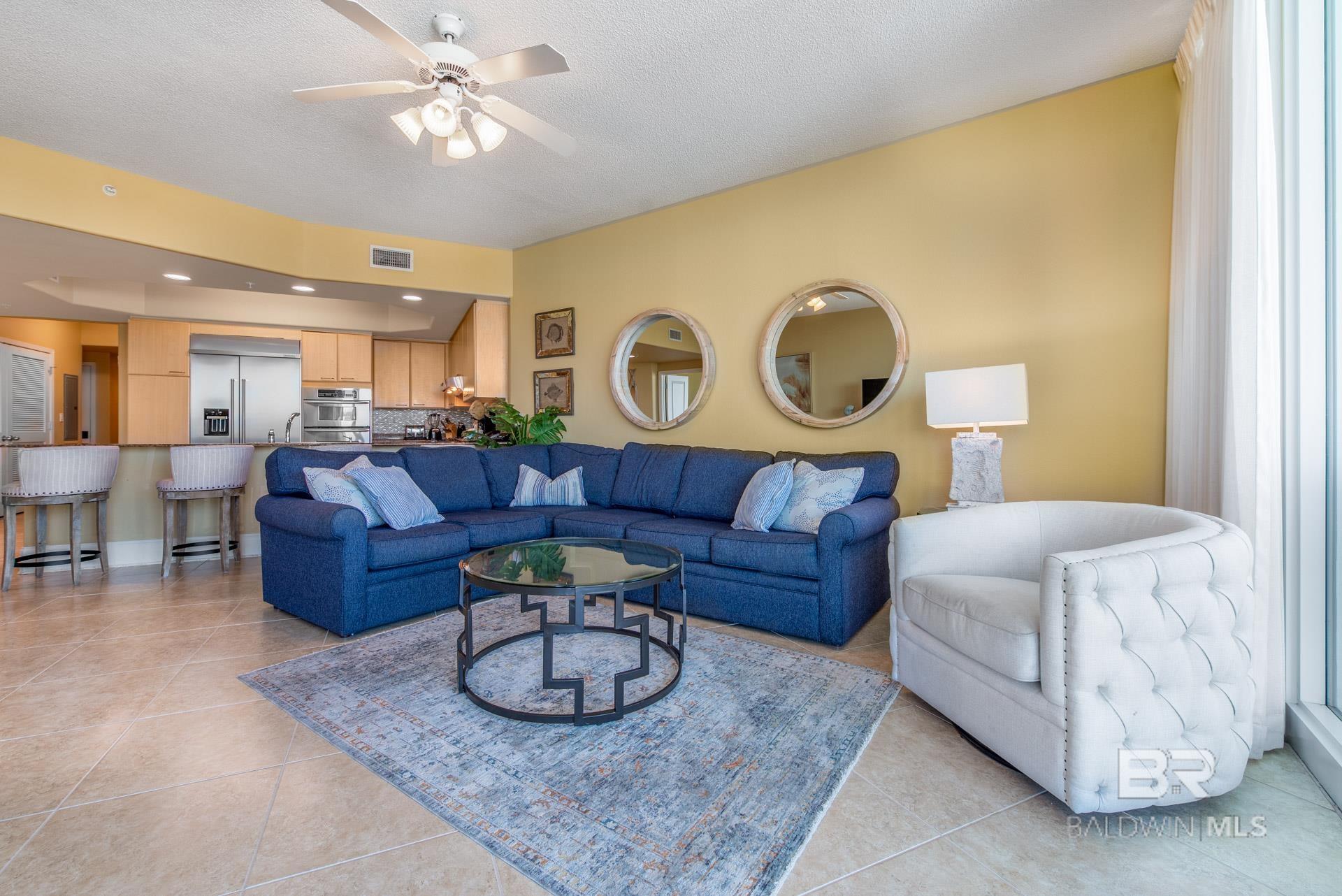 Living area featuring a ceiling fan and light tile patterned floors