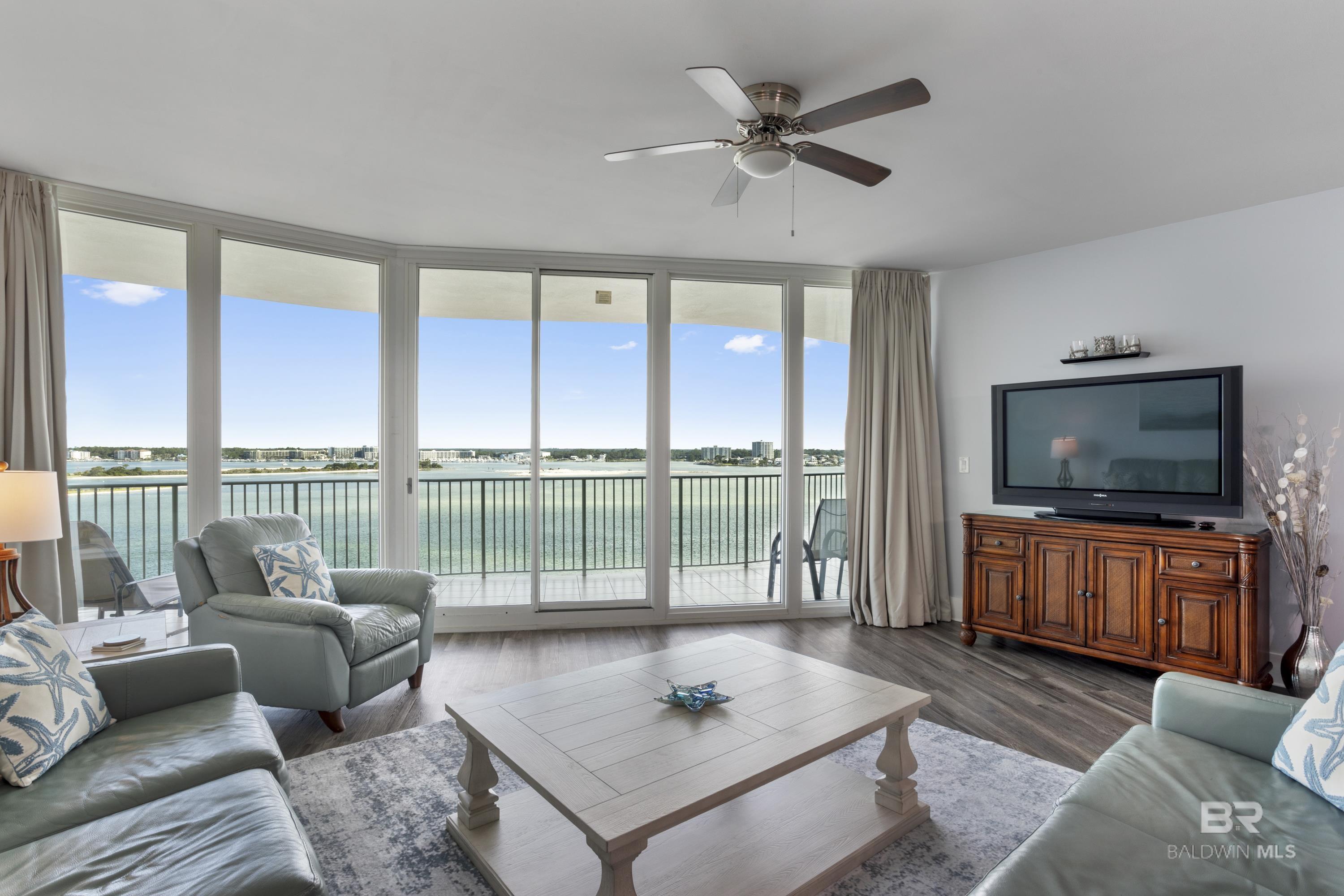 Living room with a water view, ceiling fan, and wood finished floors