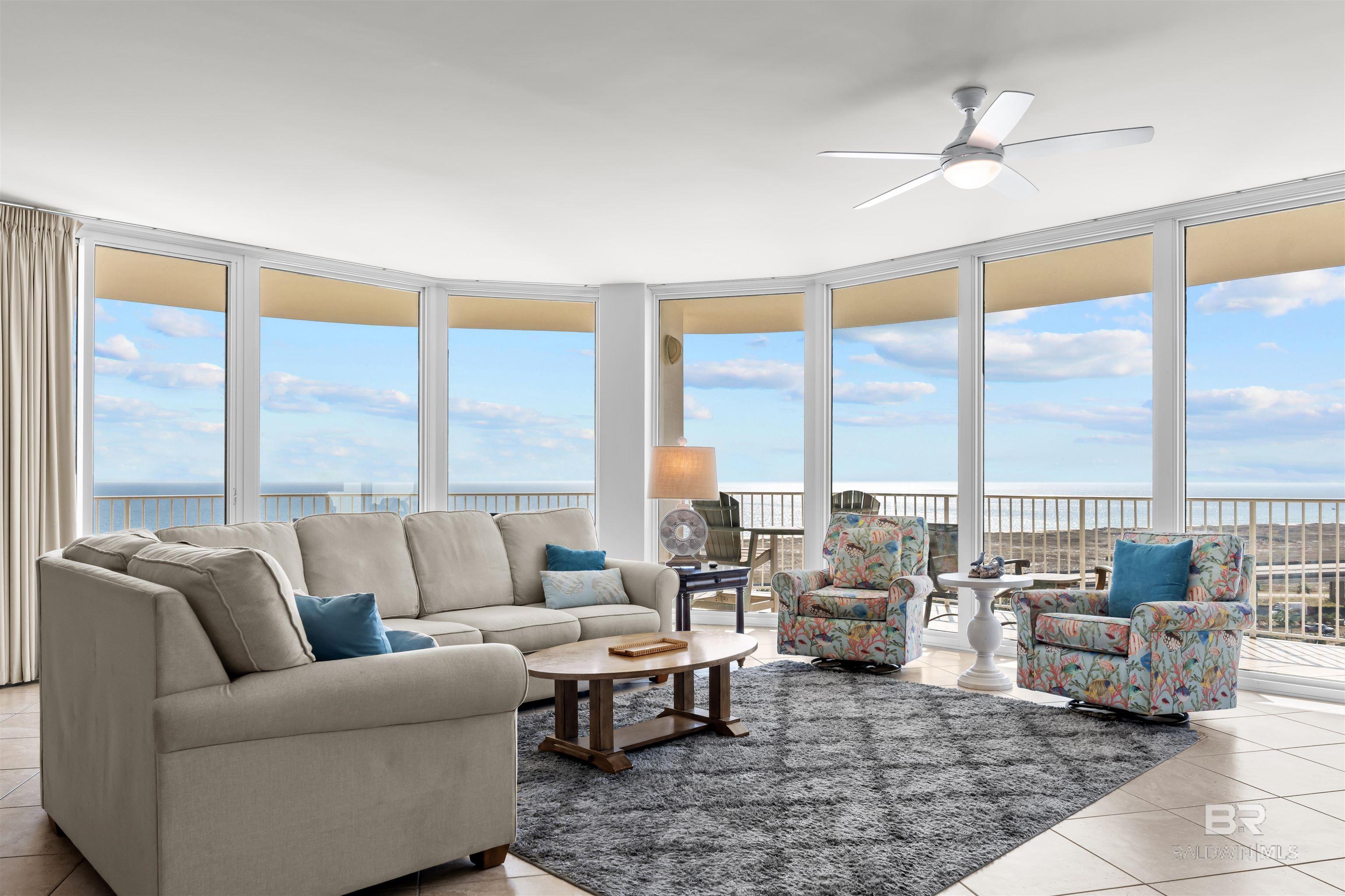Living room with light tile patterned flooring, expansive windows, a water view, and ceiling fan