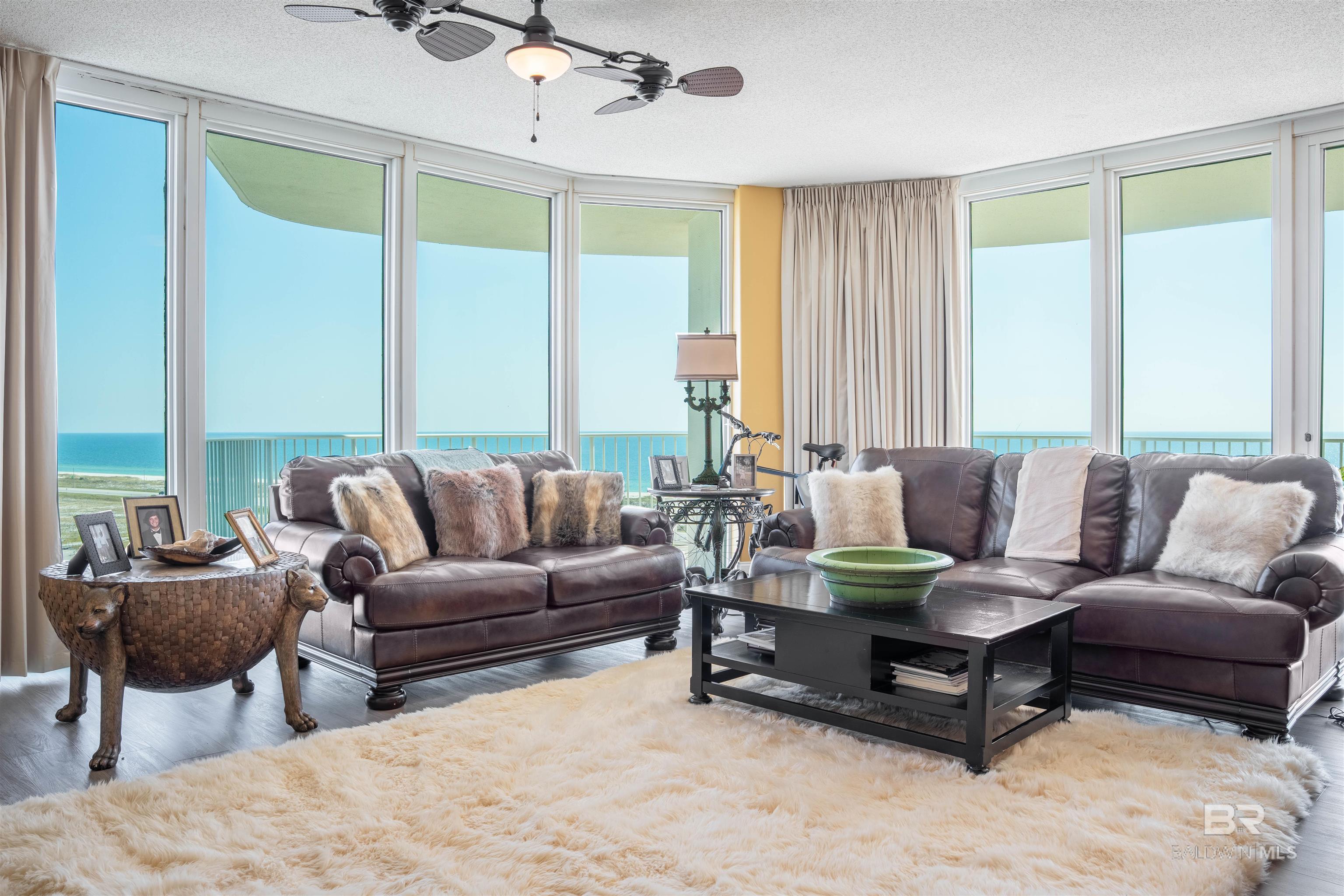 Living area featuring floor to ceiling windows, a water view, wood finished floors, a textured ceiling, and ceiling fan