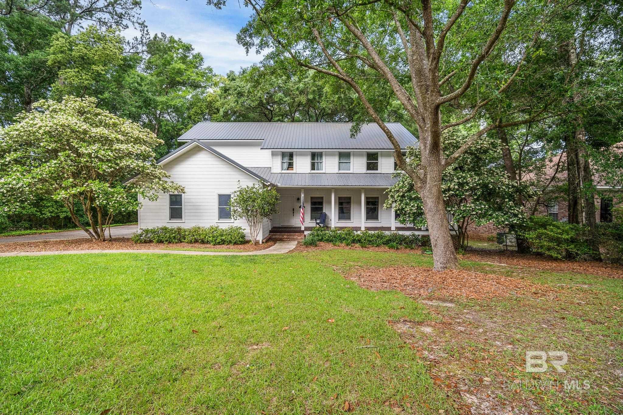 Located in the heart of beautiful downtown Fairhope, this home is Southern charm perfection! Sit a while or welcome your guests on the big, wrap-around front porch where relaxing and sipping sweet tea is a must. Once inside you will find hardwood floors, crown molding and custom wood detailing throughout. The home provides plenty of space for everyone including a living room AND a gathering room with a soaring ceiling and lots of natural light. You will love the kitchen with recent upgrades that include gorgeous granite countertops, tile backsplash and stainless appliances. There is also plenty of storage in the walk-in pantry, complete with custom shelving. On the main floor you will find the laundry room, located right off the garage and a lovely, updated half bath. The spacious primary bedroom is also located on the main level, and it too has hardwood floors and an updated bath with dual sinks, granite countertops and a custom tiled shower with bench. It also has its own private entrance to the back porch. Once upstairs, you will love the bonus/flex space that could be an office, sitting area or reading nook. There are four additional bedrooms upstairs, along with two additional full baths. Don't forget about the wonderful & private outdoor space in the back, complete with an open and screened porch. Both spaces are perfect for relaxing and enjoying the fenced yard and beautiful mature trees. This home has a newer metal roof and both HVAC systems have been upgraded in the last few years. It is conveniently located on a quiet cul-de-sac and it's only a short trip to all things Fairhope. If this sounds right up your alley, don't wait because it won't be available long!