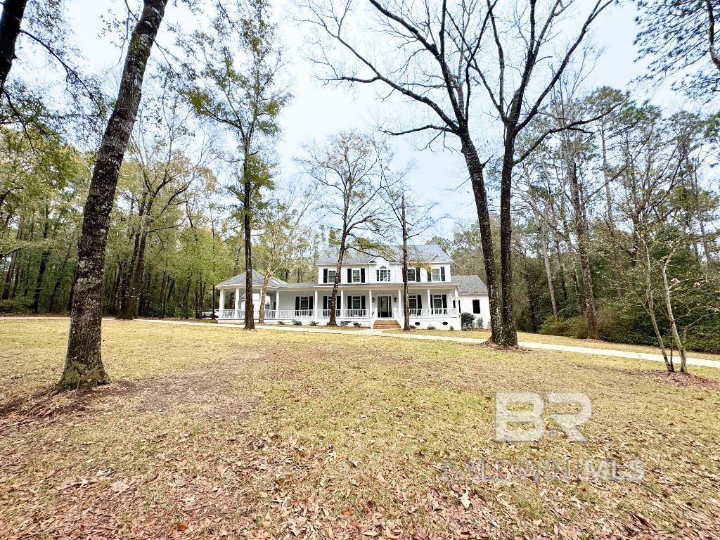 This custom-built residence nestled on a 3+ acre lot in the heart of Daphne, conveniently located off HWY 90 on a quiet cul-de-sac surrounded by trees and deer. The property features a resort-style saltwater pool with waterfall and a built-in hot tub. Fenced outdoor oasis, complete with a covered patio, built-in grill, outdoor kitchen storage, and space for beverage coolers and a beer tap.  A gourmet kitchen with oversized storage island, double wall oven, warming drawer, and custom lit cabinetry. Enjoy meals in the eat-in kitchen or gather in the adjacent hearth room, featuring a wood-burning fireplace and views of the pool. Formal gatherings can be found in the dining room, which can also serve as a versatile game room with custom barn doors.   The main level boasts a master suite, complete with a gas fireplace, office area, and access to the patio deck and hot tub. The master bath indulges with heated radiant floors, double vanities, jetted tub, and a walk-in shower. The closet offers ample storage from floor to ceiling with built-in cabinets and drawers. Also on the main floor is a two-story living room, a secondary bedroom, laundry room, and half bath.   A four-car garage with a workshop area, also features a 2nd laundry room and half-bath with easy access to the pool!  Upstairs find two bedrooms, each featuring ensuite bathrooms. You will also find a craft room with built-in cabinets being used as a bedroom currently. The expansive movie theater room offers endless entertainment possibilities.. With its built-in closet, it could also easily work as a 6th bedroom with its attached half-bath.  New fortified roof and AC unit in 2022. This exceptional property includes an active termite bond, transferable to the new owners. Alarm system, ring security cameras, and much more! $5,000 carpet allowance. Don't miss this rare buy opportunity!