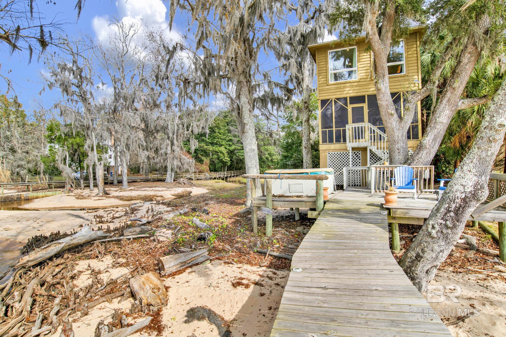 When you live on the Bay some consider the front of the house is the side facing the water! No grass to mow!! This Is The Life! Magnificent Sunsets, Jubilees, Fishing, Water Skiing and the sound of nature. Grand Hotel and Fairhope Yacht Club are a short boat ride. What more could you ask for. You will love this cozy and charming 2 bedroom, 3 full bathrooms, two story home with spectacular views of Mobile Bay. The kitchen features beautiful cabinets, wood floors, stainless appliances, granite countertops and a wine cooler. The open and airy light filled family room has wood floors, a gas fireplace and many windows which allows for the great view of Mobile Bay and watching the sunset. You can enjoy your morning coffee on the screened-in poarch which is off of the family room. Upstairs you will find the spacious master suite that will provide you with the peaceful view of Mobile Bay. Imagine waking up to that view every day. The additional bedroom is also upstairs and has its own private bath. Walk outside and choose your activity, sit and relax on your own private pier or maybe enjoy a few water activities. You can walk the beach area, trap crabs or even witness a Jubilee which can happen several times during the summer. I'm told the Jubilee only takes place in two areas of the world this 18 mile beach and in Japan. The pier features a 5000 pound boat lift which makes water activities easier. Boat to the Grand Hotel, Fairhope Yacht Club or maybe over to the Causeway for dinner, you can choose your own destination. There is a whole house generator and hurricane covers for the windows of the house. Great location for a family to live or as a vacation retreat, this home is ideally positioned to enjoy the proximity to beaches, cafes, restaurants, shopping, and schools, Easy access to the interstate for travel to Mobile and Florida. This home provides all the elements for relaxing, comfortable and easy living. Buyer to verify all information during due diligence.