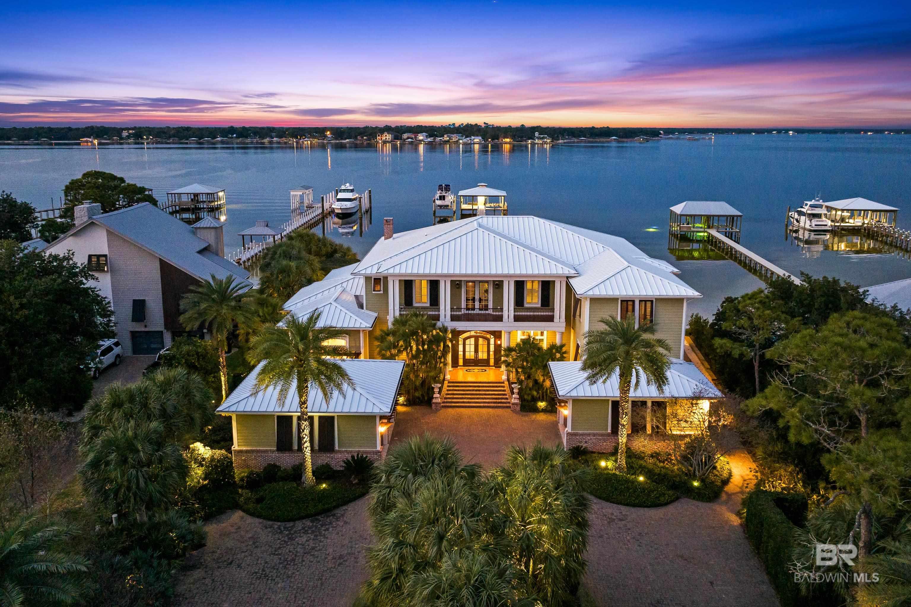 Welcome to 30147 Ono Blvd in Orange Beach, AL. This stunning home is perfectly nestled along the shores of Bayou St John on one of the most desirable streets on Ono Island. Featuring five bedrooms with five full bathrooms, three half bathrooms, and 7,840 square feet, this luxurious custom built home offers a beautiful blend of traditional elegance and serene waterfront living, which creates the perfect private oasis with a touch of Southern charm! The heart of this home is the spacious open-concept living area that seamlessly connects the indoor space with its coastal outdoor environment. The main level features beautifully detailed 12' ceilings, a large living room and dining room, the primary suite, an office, a handcrafted pub for gathering, and a chef's kitchen with a keeping room, gas fireplace, butler’s pantry, and utility room. The kitchen features pecky cypress ceilings, two large islands with granite countertops, under cabinet and toe kick lighting, Rohl faucets, and custom cabinetry. The primary suite offers stunning views of Bayou St. John with direct access to the patio and a massive spa-like bathroom with his and her walk-in closets. The second level features four guest suites, a bunk room, additional laundry room, and a separate living room with a kitchen and access to a spacious balcony offering breathtaking views. No expenses nor details were spared in this home featuring top shelf finishes and appliances, elegant crown molding throughout, luxurious tile plank floors, cabinetry by Julian Brock, hand-crafted Rohl faucets, eight foot solid mahogany wood interior doors, an elevator, geo-thermal heating and air conditioning system, and a 50kW whole home generator. The exterior features an amazing outdoor living space with a fully equipped kitchen, fireplace, heated saltwater pool and spa, a private beach area, aluminum heavy gauge standing seam roof, 40x40 covered boat house with ThruFlow decking, a storage room and two boat lifts. Buyer to verify all in