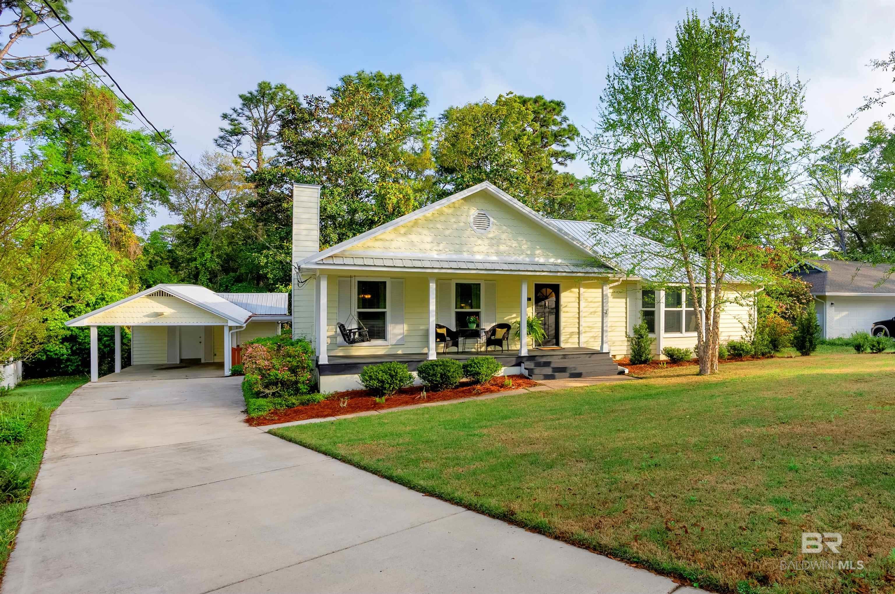 This Downtown Fairhope cottage has classic charm and an abundance of upgrades!  You will be welcomed by wood floors, fresh paint, and an inviting open-concept living and dining room lay out - perfect for relaxing or entertaining. This meticulously maintained home boasts a new sunroom AC (2024), tankless water heater (2022), fortified metal roof (2020), and impact-rated windows (2016) throughout. The light-filled 12' x 12' sunroom offers a peaceful retreat, overlooking a private backyard with mature landscaping. The updated kitchen is a chef’s delight, featuring quartz countertops, stainless steel appliances, and a deep utility closet/pantry with ample storage. You will enjoy additional features including spacious walk-in closets, a convenient storage closet in the carport, and a large outdoor workshop. Designed for efficiency and comfort, the home is equipped with natural gas servicing the fireplace, dryer, water heater, and offering available hookups for the range and an outdoor generator. Out front the covered porch, new driveway, and two newly planted live oak trees add to the home’s Southern charm. Don’t miss this rare opportunity to own a move-in-ready gem in the heart of Fairhope—schedule your showing today! Buyer to verify all information during due diligence.