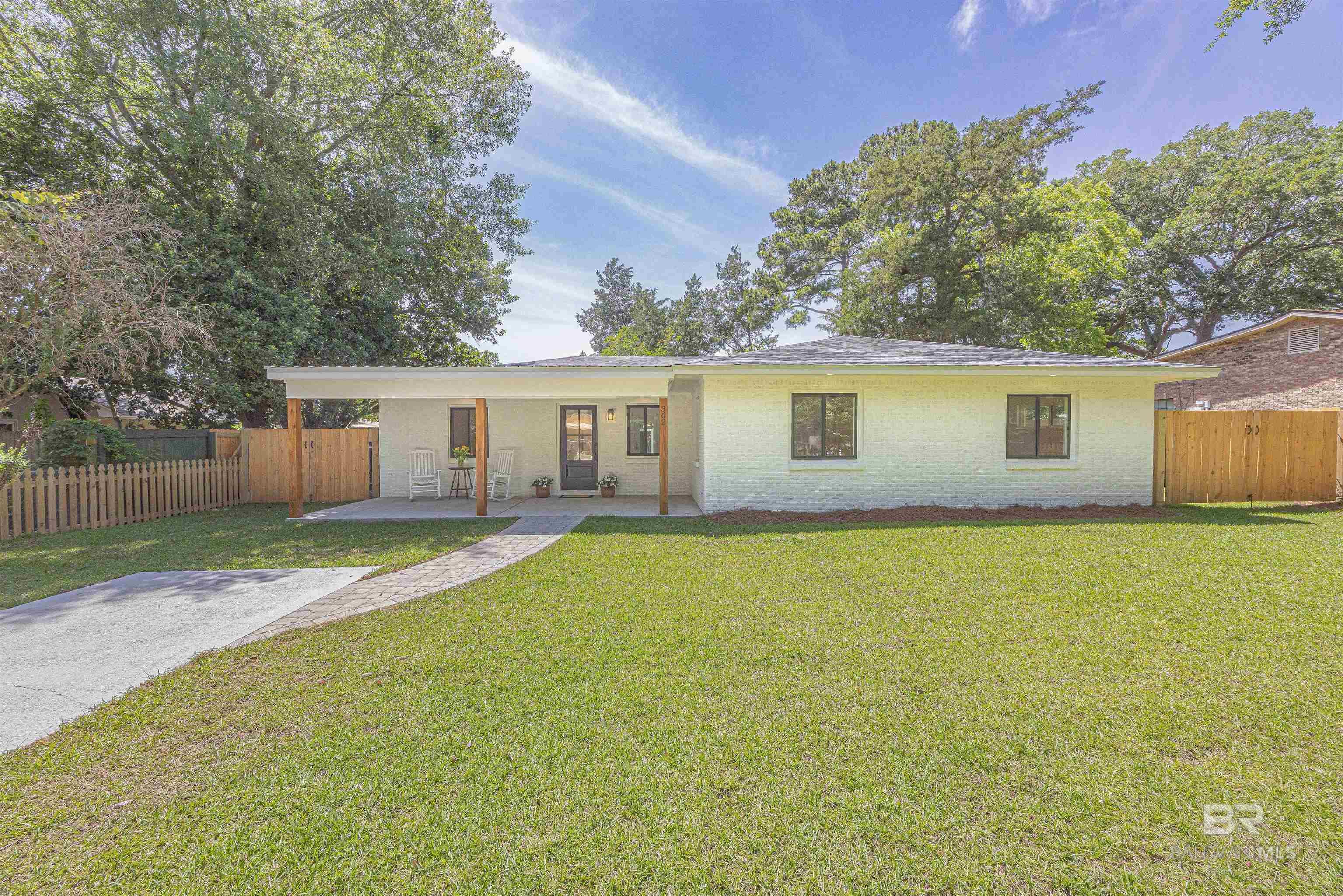 Welcome home to a deeded Fairhope cottage on a lot and 1/2.  This charming, completely renovated cottage is ideally situated within walking distance of downtown Fairhope, Alabama. Every detail has been meticulously updated, leaving no surface untouched. The home has a new roof, impact-resistant windows, and entirely new plumbing and wiring, ensuring modern comfort and safety. Inside, you'll find wood, tile, and split brick flooring throughout, complementing the open and split floor plan that enhances the home's spacious feel.  The primary bedroom offers a special retreat with access to a secluded paver patio, just the place for morning coffee or evening relaxation. A welcoming rocking chair front porch invites you to enjoy the neighborhood's charm. Convenience is key with a carport accessible via the alley entrance behind the home, providing easy access and covered parking.  At the rear of the property, an impressive storage building awaits. This two-room structure is equipped with power, offering versatile space for a workshop, studio, or additional storage needs. Adjacent to this is a pergola area, ideal for enjoying Fairhope's pleasant evenings. The amazing backyard provides a serene setting for entertaining guests or unwinding in solitude.  This property seamlessly blends modern updates with the timeless appeal of Fairhope's historic charm, making it a rare find in a coveted location. Home has applied for Silver Fortification Certification, if confirmed could save on insurance. Buyer/Buyer's agent to verify all items deemed important during the due diligence period.  Buyer to verify all information during due diligence.