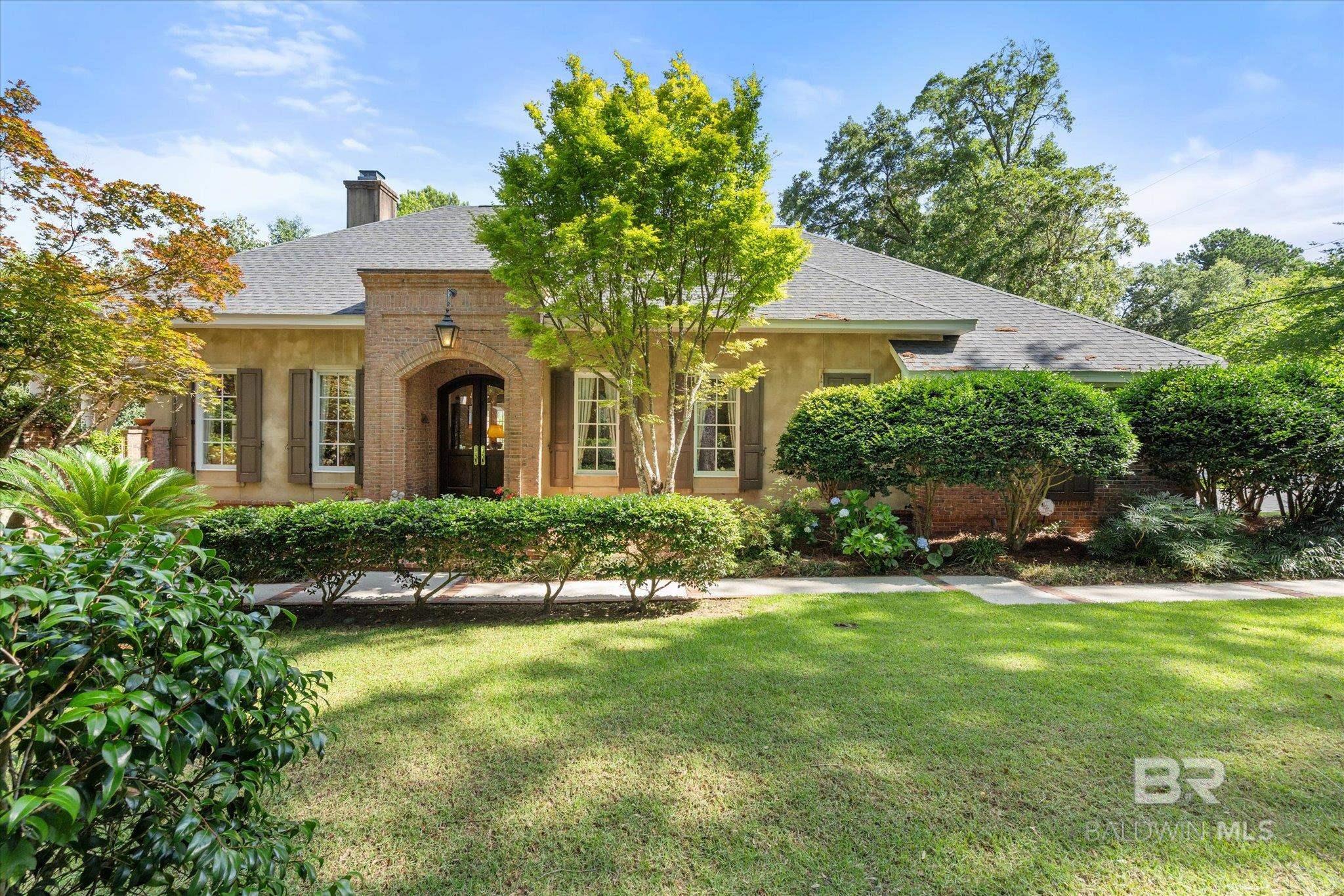 This one-owner custom-built home, nestled in the charming Old Daphne neighborhood, is designed with entertaining in mind and offers a warm, inviting atmosphere throughout. The open floor plan allows for seamless flow between spaces, making it perfect for hosting guests or enjoying family time.  French doors throughout the home create an airy, bright environment, letting in natural light and connecting the inside to the outside. A standout feature of the home is the wonderful side court yard, complete with a tranquil fountain, which opens directly to the family room and the oversized master suite. The master bath is a true retreat, offering a double vanity, Jacuzzi tub, separate shower, and an expansive walk-in closet with custom shelving and drawers. The living and family rooms both exude elegance, with the family room boasting a fireplace flanked by built-in bookshelves. The living room features an entire wall of bookcases, perfect for showcasing your collection or adding a cozy touch to the space. Heavy crown molding and New Orleans-style baseboards add sophisticated detail throughout the living areas. The split-bedroom floor plan provides privacy, while the master suite is spacious and luxurious. The attic offers potential for expansion, with plenty of room to add more bedrooms, and the hall is wide enough to accommodate a staircase leading to a potential upstairs. A separate staircase in the garage provides easy access to the attic space. Outside, the home is surrounded by lush, mature landscaping that enhances its curb appeal. There's a separate parking pad in addition to the double garage, and a dedicated well for irrigation ensures the landscaping stays lush year-round.  The home also features a central vacuum system, providing added convenience, and ample storage throughout.  Recent updates include a new roof installed 2 years ago, ensuring peace of mind for the new owner.  This home combines modern comforts with timeless charm and is ready to welcome you. B