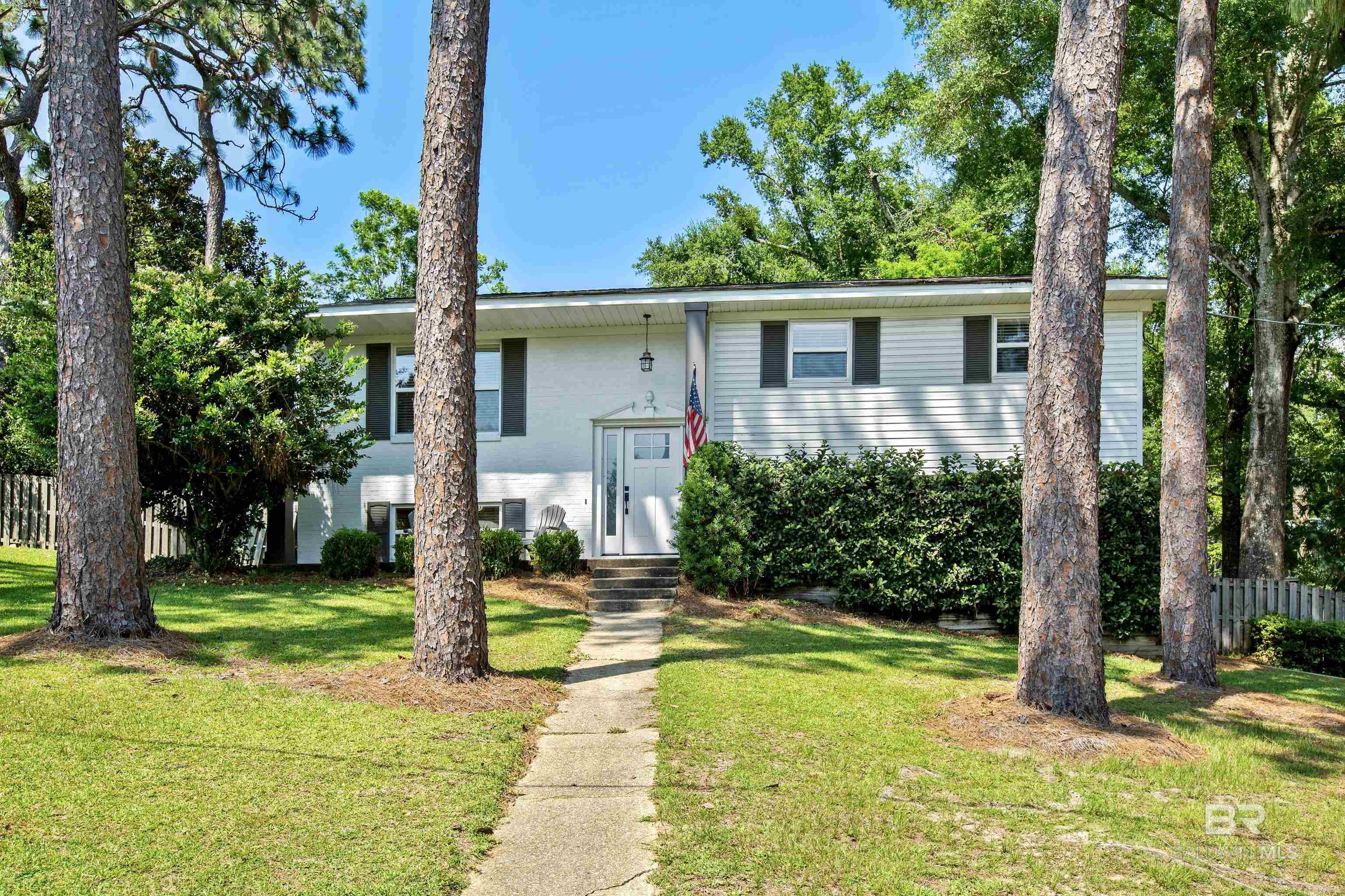 Welcome to the beautiful Fairwood neighborhood in Fairhope! This beautifully remodeled home is situated on a large, shaded corner lot in walk-able distance to Downtown Fairhope or hop in your golf cart and enjoy a short ride to Mobile Bay for a beautiful sunset! This split-level home offers beautiful hardwood floors on the upper level throughout. The remodeled kitchen offers vaulted ceilings with tons of natural light, granite countertops and stainless appliances. Step out on the huge deck to enjoy the views of the backyard and quiet neighborhood. The upper level offers 3 bedrooms, all with hardwood floors and remodeled bath with beautiful tiled tub/shower. The lower level has a 4th bedroom which is currently used as the Primary with a huge closet/flex room attached. Also, enjoy a covered patio just off this bedroom. The 2 car garage is a huge bonus in this neighborhood! Call today to see this wonderful home located close to downtown Fairhope! Buyer to verify all listing data to satisfaction during contingency period. Information deemed accurate but not guaranteed. Buyer to verify all information during due diligence.