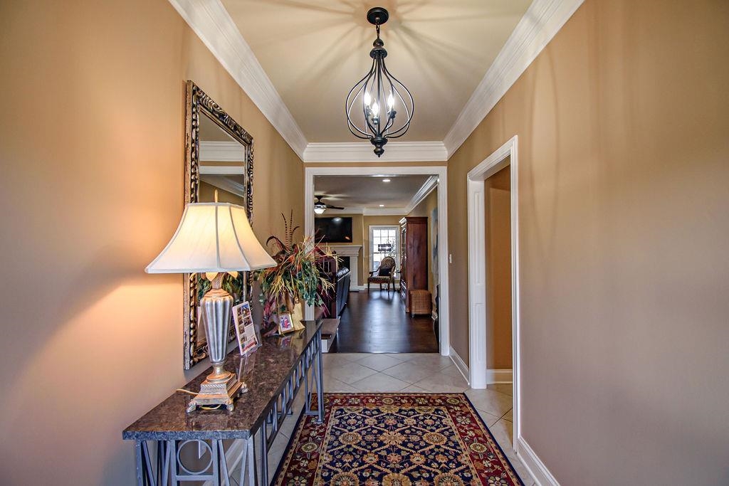 Elegant entry featuring double doors,  chandelier, ceramic flooring, and crown moulding.