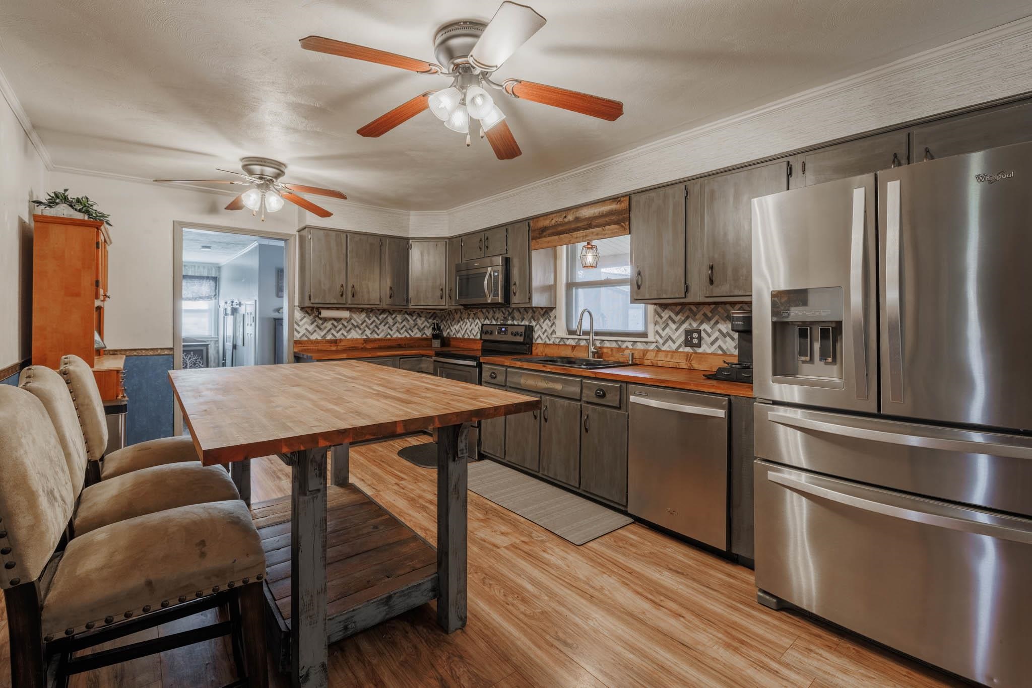 Stainless steel appliances, tiled backsplash, butcher block counter tops and table.