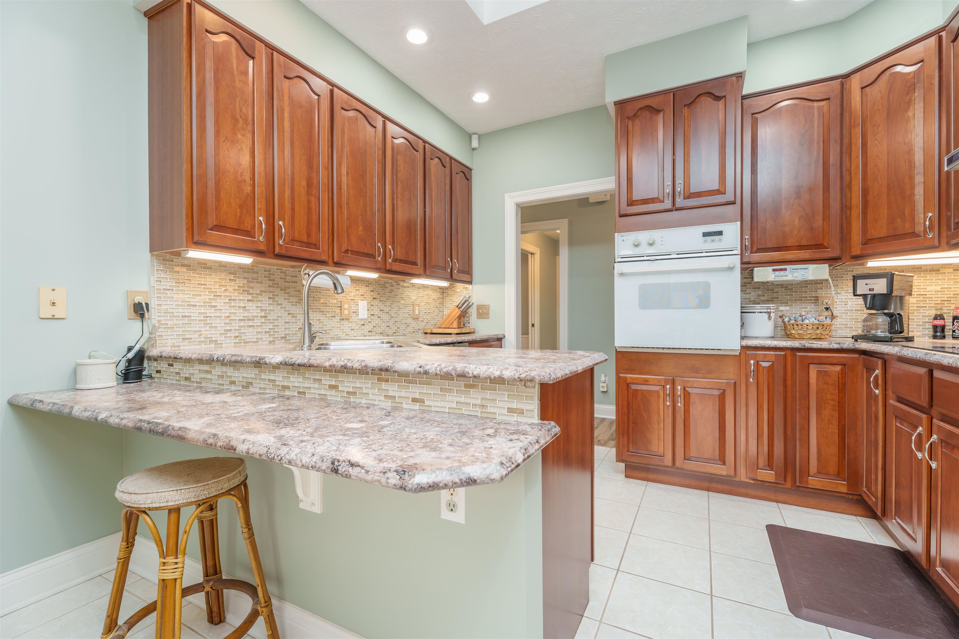 Beautiful naturally lit kitchen with cherry wood cabinetry, & lighting under kitchen cabinets.