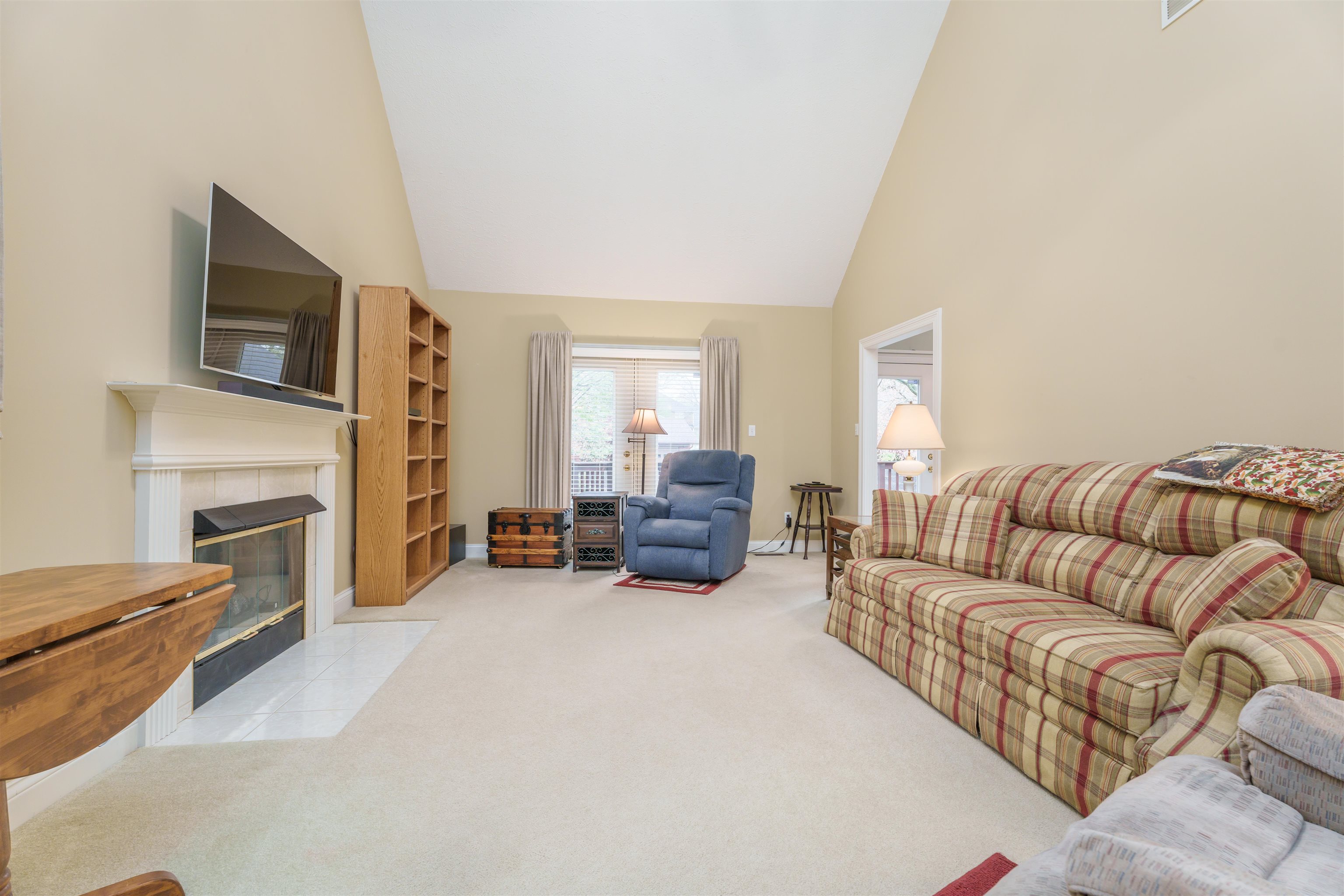 Living room has expansive high ceilings & includes a remote-controlled wood-burning gas fireplace.