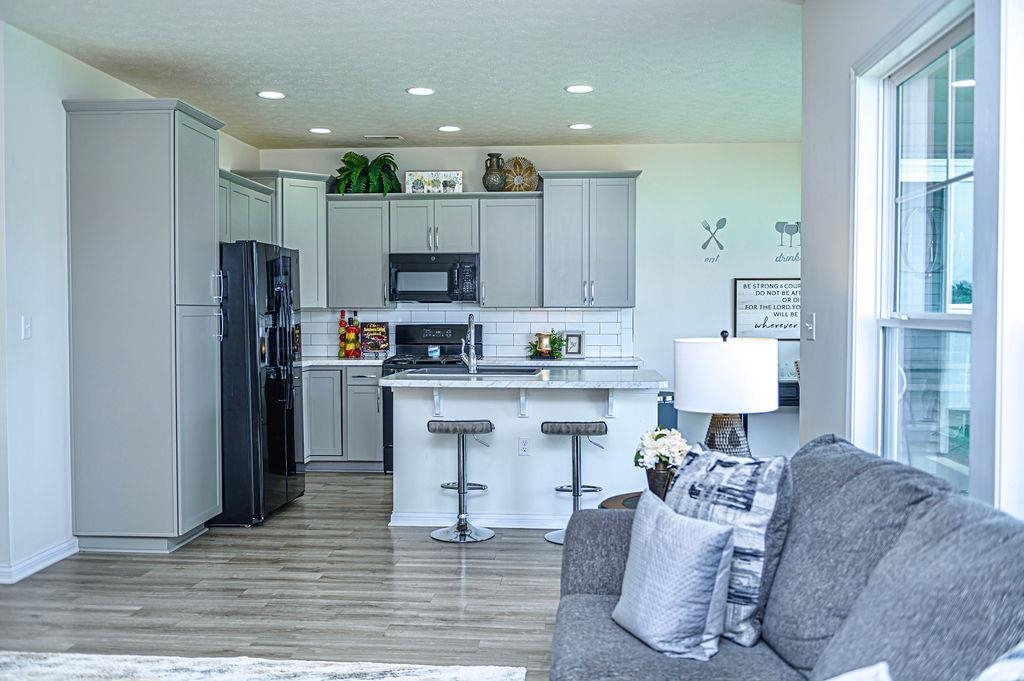 Chef's kitchen features grey cabinets, island, and appliances including a gas range.