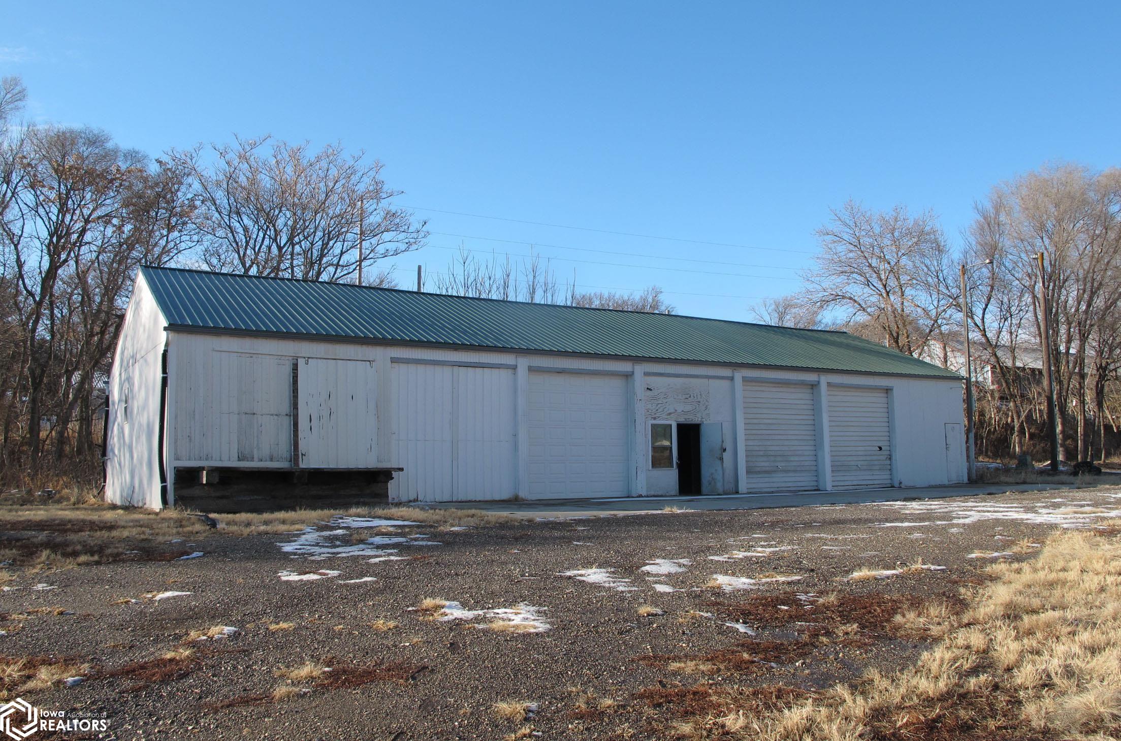View of the front of the building looking west. 3 overhead doors with 10.5 x 10.5 openings.  New roof sheeting 2021. Newer gutters. New electrical 200 amp service on N&M interior sections. City water & sewer available. Propane tank stays. Large lot.