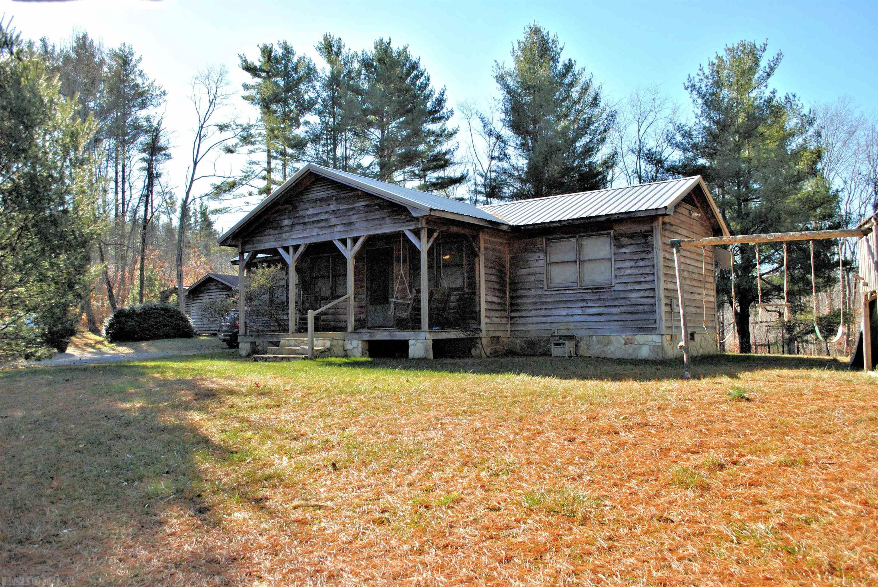 This two bedroom cabin in the woods sits on 21.796 acres in Floyd County and has a classic rocking chair front porch!  Step through the front door into a great room with exposed beams and a free standing gas heater with flue for woodstove too with a stone hearth. The rear patio door opens to the back deck overlooking the cleared fenced area around the house with a chicken coop, woodshed and garden shed. The full bathroom is spacious with a laundry area with cabinets, new shower in 2021 and room for cleaning supplies. The home boasts a brand new metal roof in 2021 and new range.  The land is divided into two tax parcels with a new survey and three Bedroom Perk Test too.  Call for your private showing or for more information!