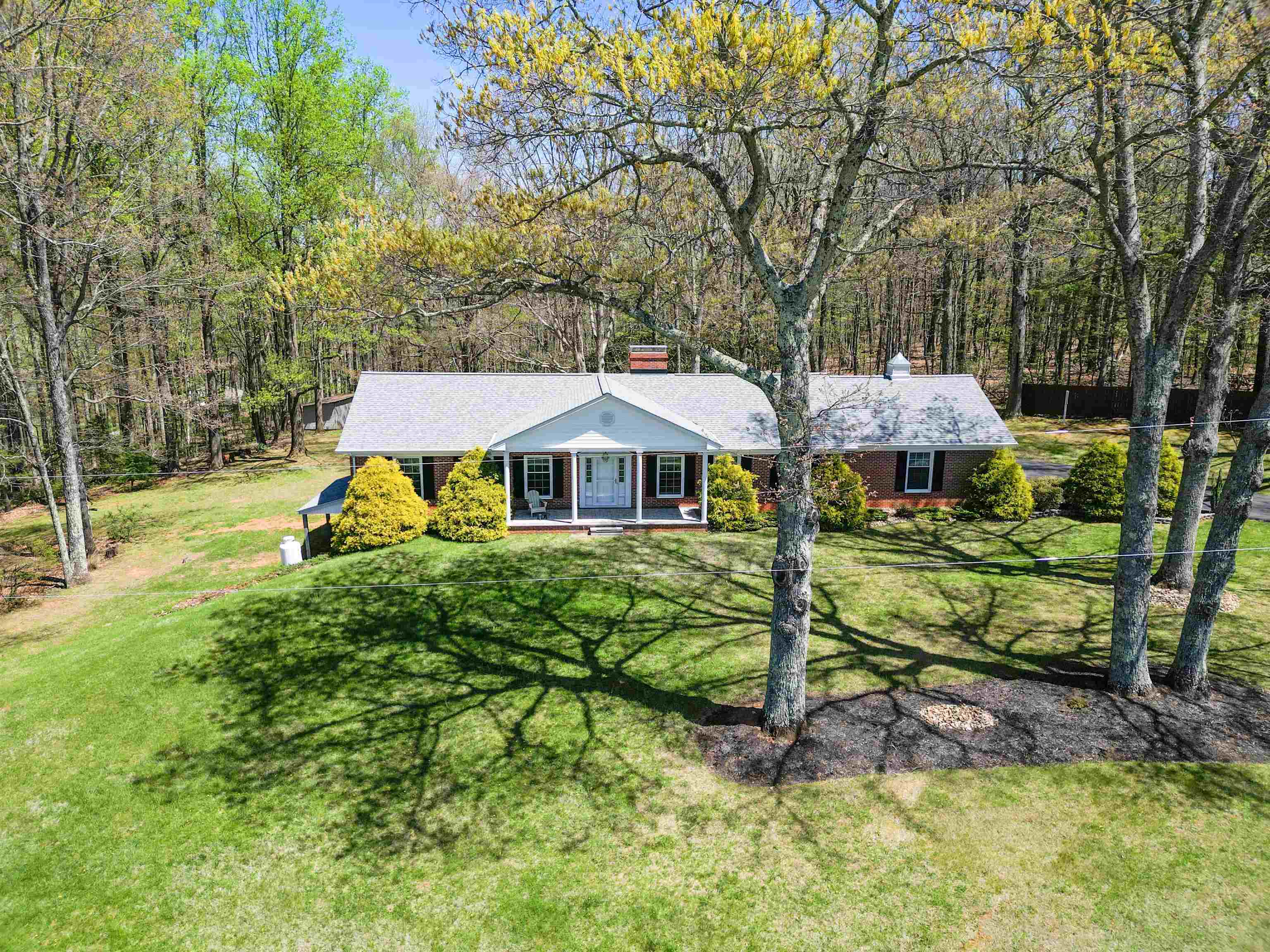 Just a quarter mile off the Blue Ridge Parkway, this move-in ready home is an immaculately maintained brick ranch on 2.83 beautifully landscaped acres. Long range views off the front porch and private views and room to entertain off the covered back deck. Main floor interior has custom cherry cabinets, hardwood floors, propane fireplaces, and granite countertops. Den has rare wormy chestnut beams, cabinets, mantle, and baseboards. Attached 2 car garage with paved driveway. Large finished basement is possible in-law suite or second income with walk-out separate entrance, bedroom/office space, full bath, den with fireplace, woodstove, and kitchen. Huge attic is floored walkable for good storage. Large storage building w potting shed. Two good wells. High speed fiber optic internet. 8 Camera security system available. New roof "22. Room for garden spaces and strolling paths. Only 5.6 miles from the town of Floyd. Click on "Unbranded Media" above for 360 degree view of main floor.