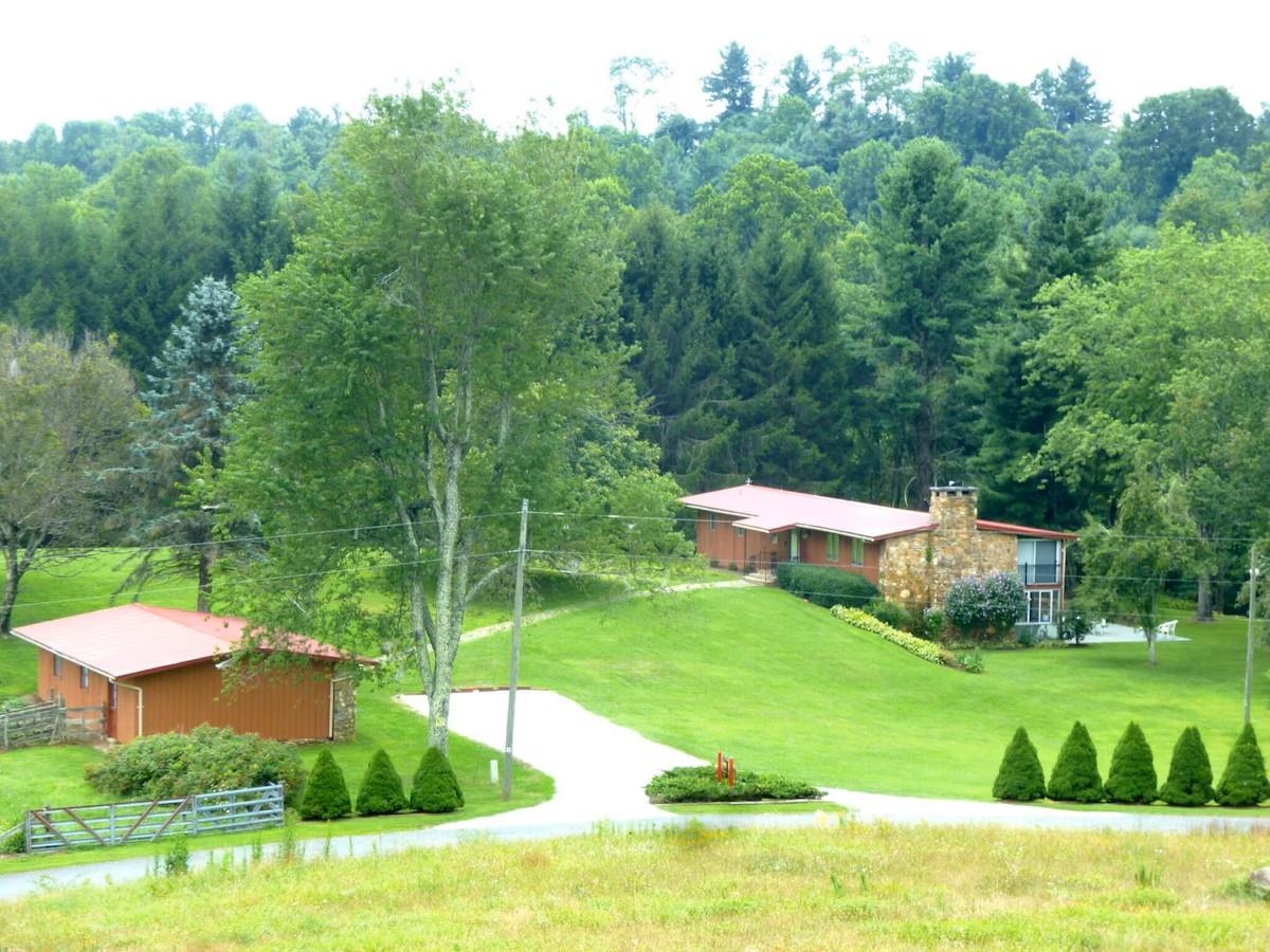Looking for a serene retreat in nature? This picturesque TURNKEY  (furnishings convey) vacation income producing 18.2-acre property boasts a beautiful 3-bed, 3-bath home with approximately 3,000 sq ft of living space combined on both the main and lower. Enjoy the peacefulness of a beautiful spring-fed pond complete with a dock, perfect for relaxing or fishing. The large sunroom offers panoramic views of the water, while a cozy fire pit is ideal for gatherings under the stars. Approximately 12 acres of open pasture, ideal for hay production or livestock. With the convenience of a Generac generator system, this home ensures both comfort and functionality.  Further enhancing the property is a 3-bay detached garage for storage and projects. Located just off the Blue Ridge Parkway, with easy access to Meadows of Dan, Highway 58, and Interstate 77, this property is perfect as a family home or mountain vacation retreat. Don't miss this opportunity to make this gem your own slice of paradise!