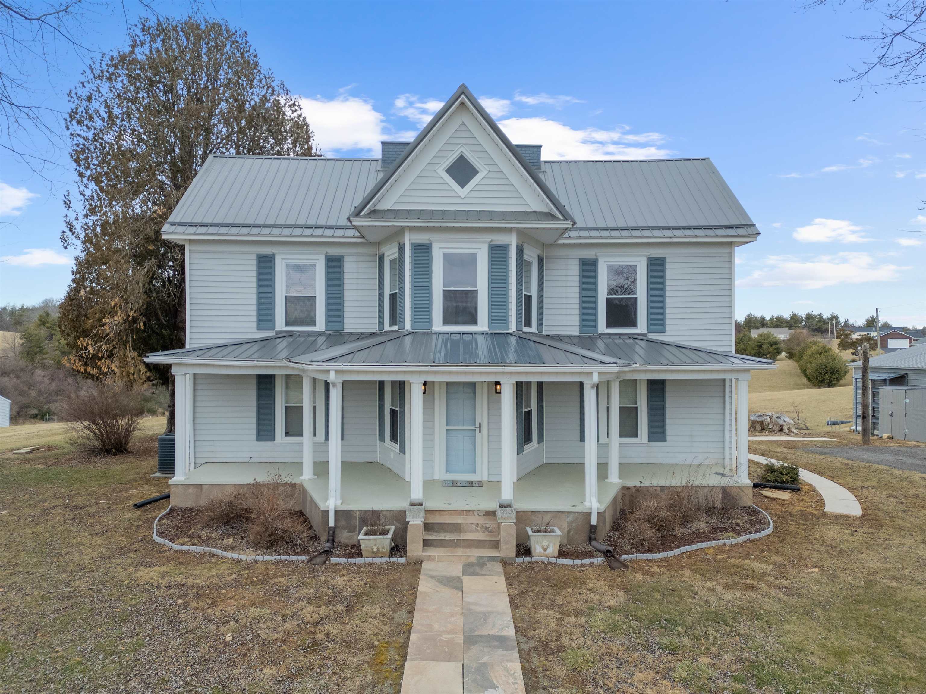 Step into this breathtaking circa 1900 farmhouse, where rustic charm meets modern convenience! Nestled on a pristine property in the desirable Woodlawn, Virginia, this 4-bedroom, 2.5-bath home boasts timeless character and thoughtful updates. A welcoming entrance is centered below a striking canted bay window. Inside you’ll find spacious living areas filled with natural light and hardwood floors. The updated kitchen and dining spaces flow seamlessly to include a deck overlooking a pristine pond, ideal for entertaining. Modern updates go beyond the kitchen to include all bathrooms complete with recent floors, vanities, and fixtures. A recent metal roof completes the stunning aesthetic of this home. Outside you’ll also find a covered front porch with views of the Virginia countryside. A detached garage building provides ample storage or workshop potential. Just minutes to local shops, stores, and recreational attractions. A true Gem of Appalachia, let's make this property your new home!