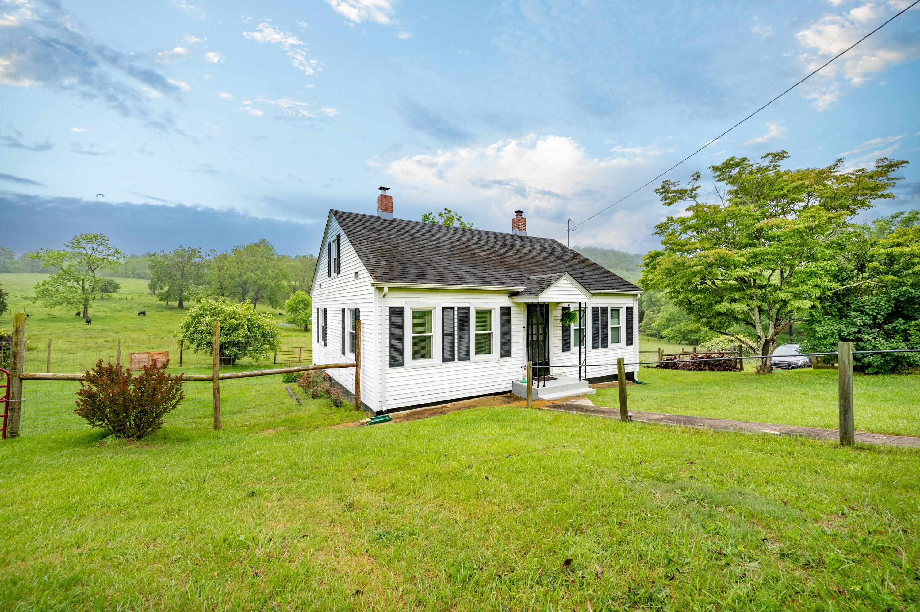 This charming country cottage is ready to become your new mini farm or weekend retreat! Nestled just minutes from Buffalo Mountain and only 13 miles from the heart of Floyd, it offers easy access to everything the beautiful Blue Ridge Mountains have to offer. Set on a spacious, beautifully maintained lot, the property features a large yard with fruit trees, established garden boxes, a grape arbor, and a variety of flowering shrubs and perennials. A deer fence surrounds the garden and backyard—perfect for keeping your pets safely in and the wildlife out. Inside, the darling home boasts roomy bedrooms, a big, bright sunroom, and a newly remodeled kitchen with an attached laundry area. The updated water filtration system ensures fresh, clean water throughout. The old spring house offers potential as a charming potting shed or a handy tool shed. A 10x18 studio/workshop with electricity provides space for creative projects, hobbies, or additional storage. This gem is a homesteaders dream!