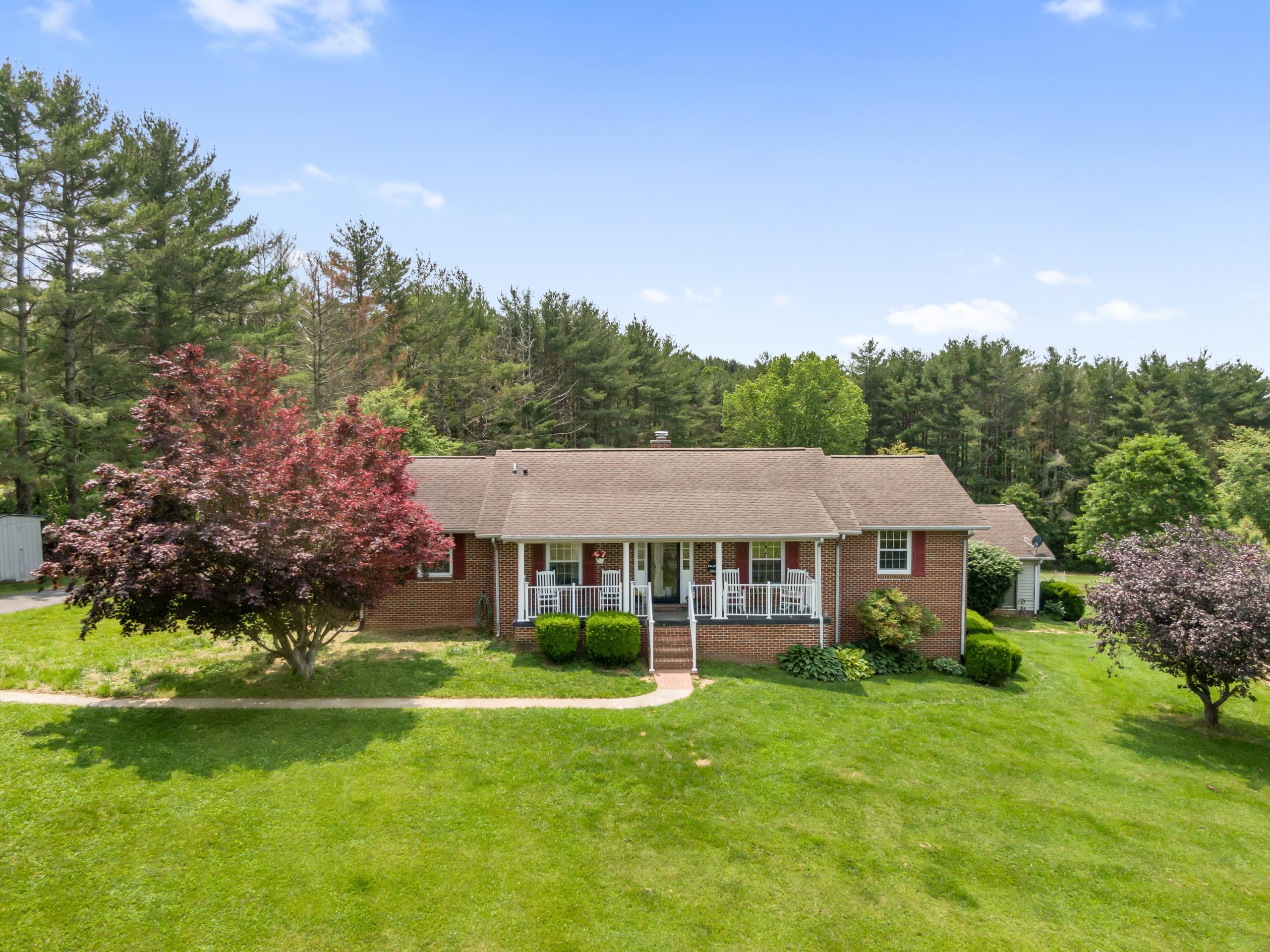Enjoy peaceful one-level living with modern updates and country charm. This low-maintenance brick ranch sits on a fully fenced, flat lot—perfect for gardening, chickens, or simply enjoying the outdoors. A new front gate, fencing, and converted chicken coop add function and flexibility. The detached oversized 2-car garage, walk-out basement garage with a single bay door, and two additional outbuildings offer plenty of storage and workspace. A paid-off solar panel system, whole-house generator, and a thermostat-regulated fireplace with a full tank ensure comfort and peace of mind. Inside, enjoy an open-concept layout with a spacious living area, updated kitchen with newer appliances, and a generous primary suite with en suite bath. Relax in the enclosed patio overlooking your private mini-farm with apple trees. A new well line adds reliability, and attic insulation boosts efficiency. The spa building rounds out this well-equipped, self-sufficient property.