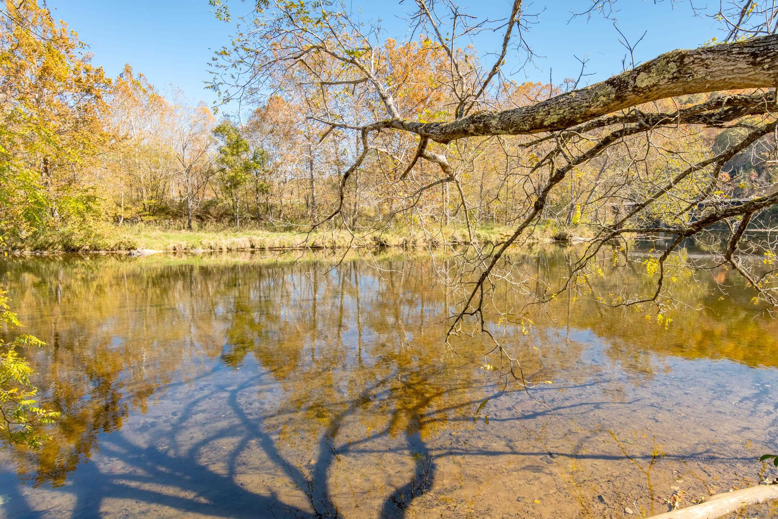 This storybook log home offers over 500 feet of New River frontage and complete privacy. Built to last with poured concrete foundations, the 2,035 sq ft home features 4 bedrooms, 3 full baths, a two-story layout, and a partially finished full basement. The living room boasts a stunning stone fireplace with a woodstove, and the kitchen is highlighted by rare wormy chestnut cabinetry. A second woodstove in the basement is ducted throughout the main level for extra warmth.  The two-car garage includes two additional stories above, perfect for a shop, storage, or a potential two-story apartment. A separate bunkhouse/cottage near the river offers its own well, septic, power meter, and full bath—ideal for an AirBnB or guest retreat. Multiple wells are located on the property.  In 1987, 14,000 pine trees were planted for lasting privacy or future harvesting. Original owners have meticulously cared for this once-in-a-lifetime riverside retreat. Furniture is negotiable.
