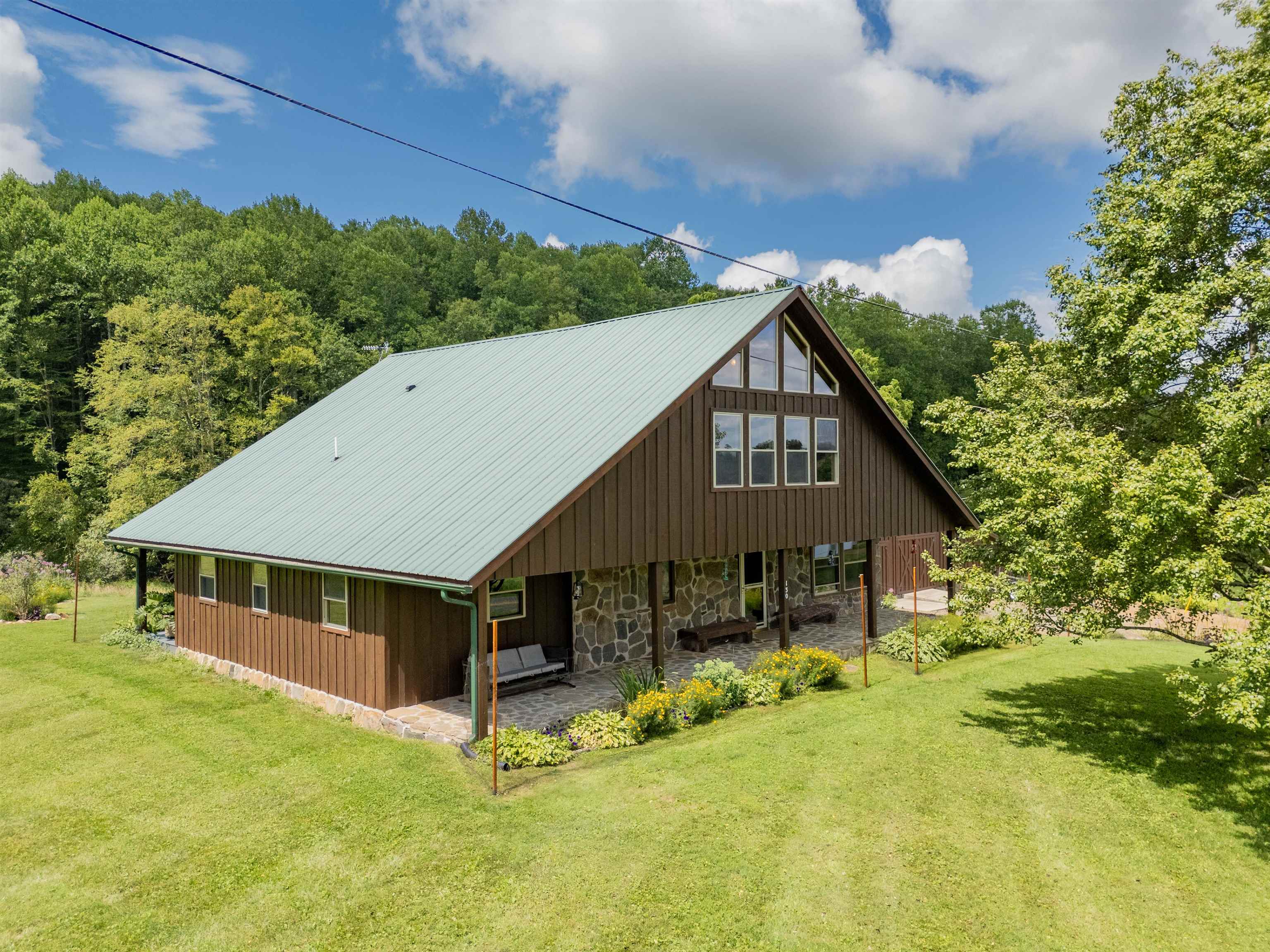 A quiet piece of paradise just off the Blue Ridge Parkway! Beautifully landscaped with flower gardens and fruit trees, this spotlessly maintained contemporary cabin offers 2,400 sq ft of living space. Handcrafted hardwood floors and unique wormy curly maple and white ash cabinetry with epoxy countertops and stainless backsplash create a truly custom kitchen. A striking stone fireplace with gas logs adds warmth to the living area. The thoughtful design incorporates the original 1940s structure into a spacious, inviting home—perfect as a family residence or vacation rental. Indulge in the luxury of a clawfoot tub and private sauna. Two detached buildings offer incredible flexibility: one functions as a radiant-heated gym/yoga studio with a peaceful deck, while the other houses a woodworking shop and lower-level workspace. A side structure provides extra storage for tools. Come experience this tranquil, one-of-a-kind mountain retreat!